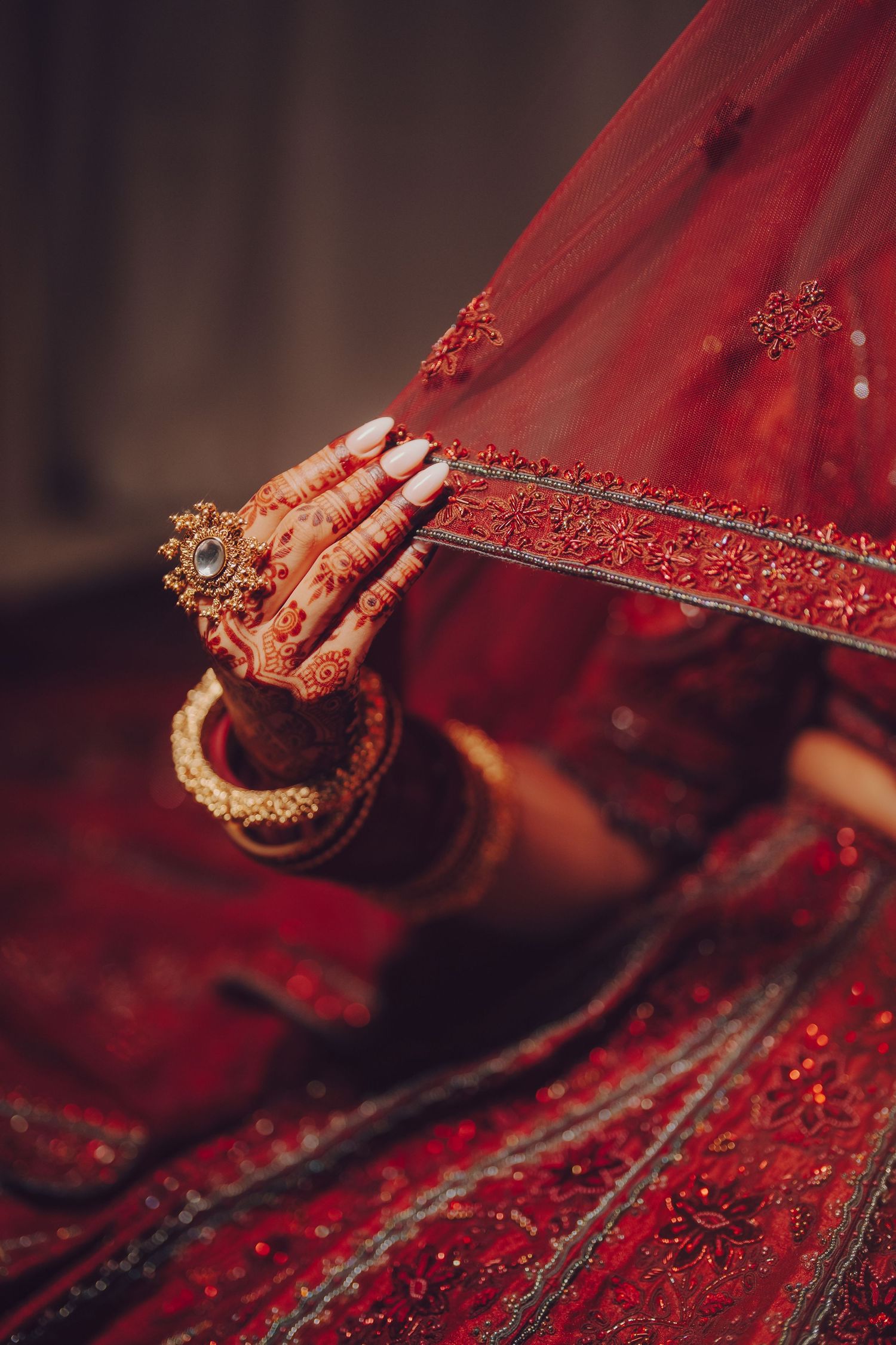 Detailed shot of red embroidered fabric with intricate beadwork and traditional Indian bridal jewelry.