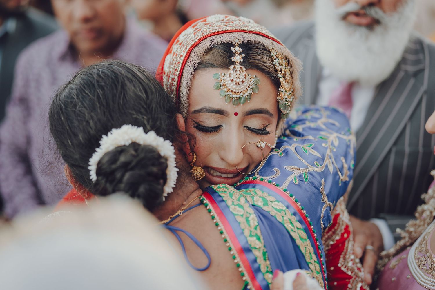 Close-up details of traditional Indian bridal jewelry and makeup with colorful embellishments.