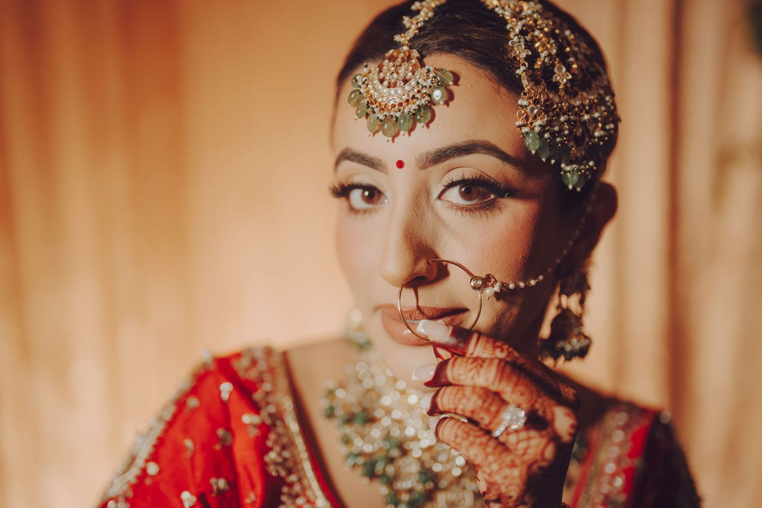Traditional Indian bridal attire featuring ornate jewelry, henna designs and red wedding attire.