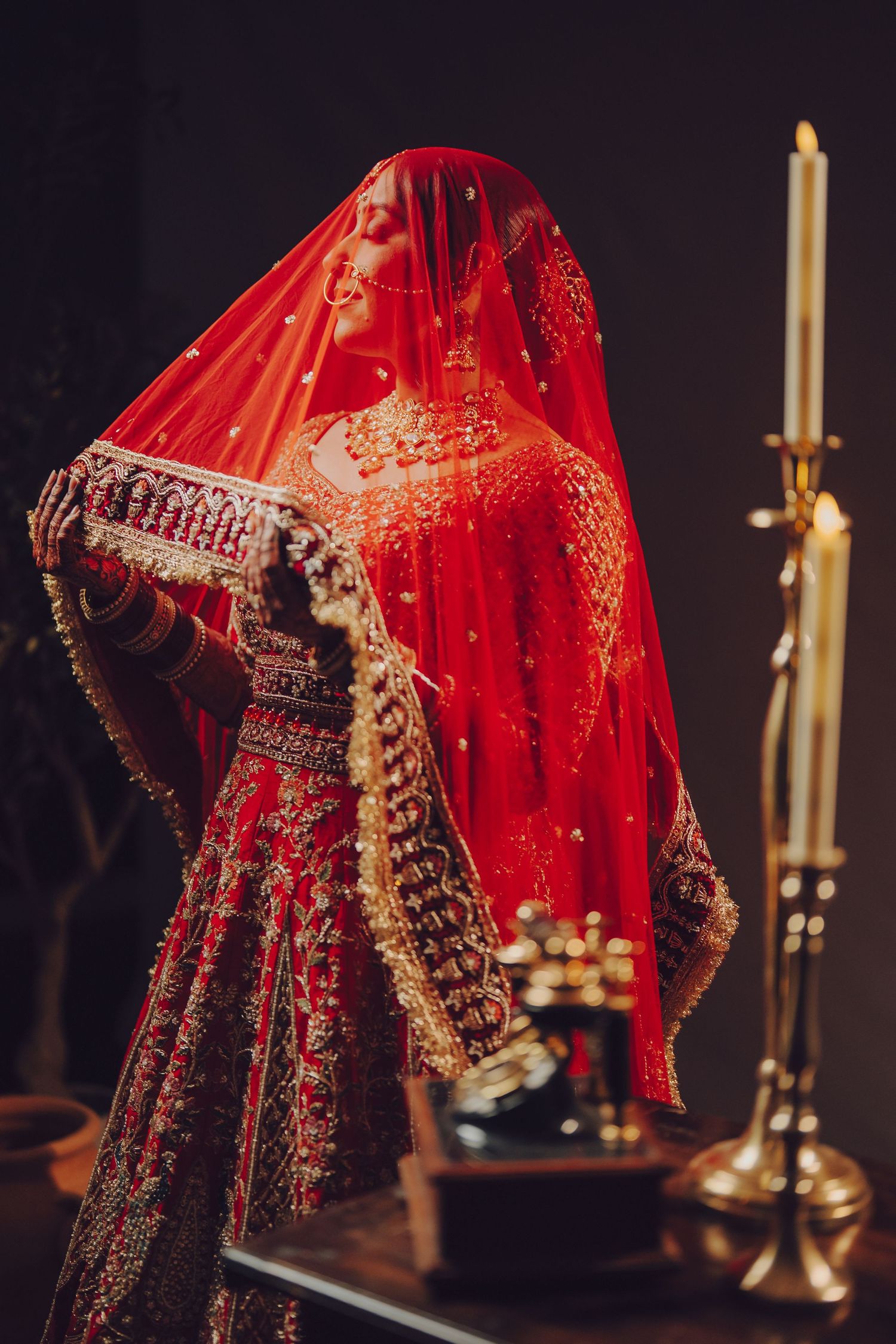 Traditional red and gold embroidered Indian bridal lehenga with intricate details captured in dramatic lighting.