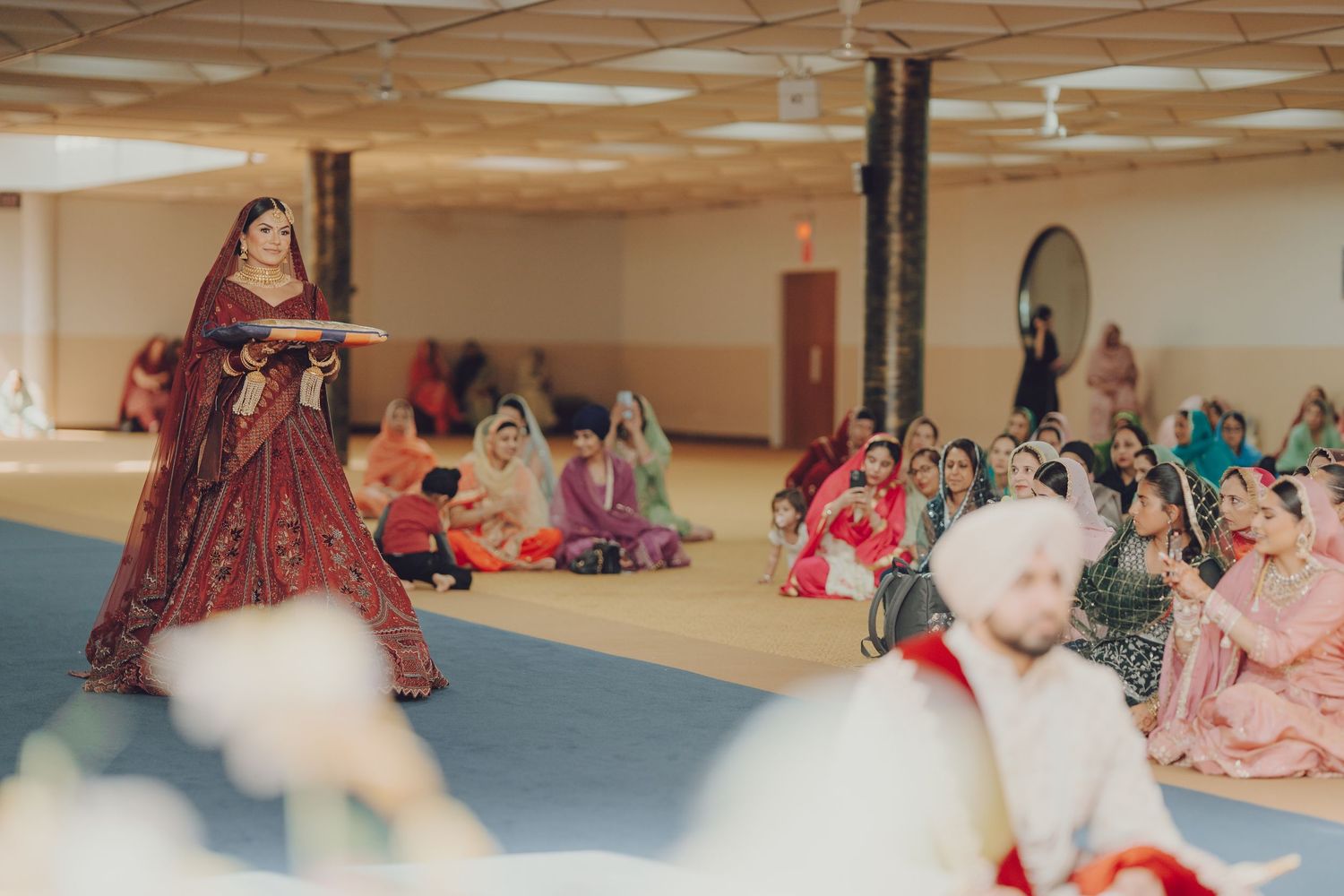 Traditional Indian dance performance in a large hall with guests seated on floor.