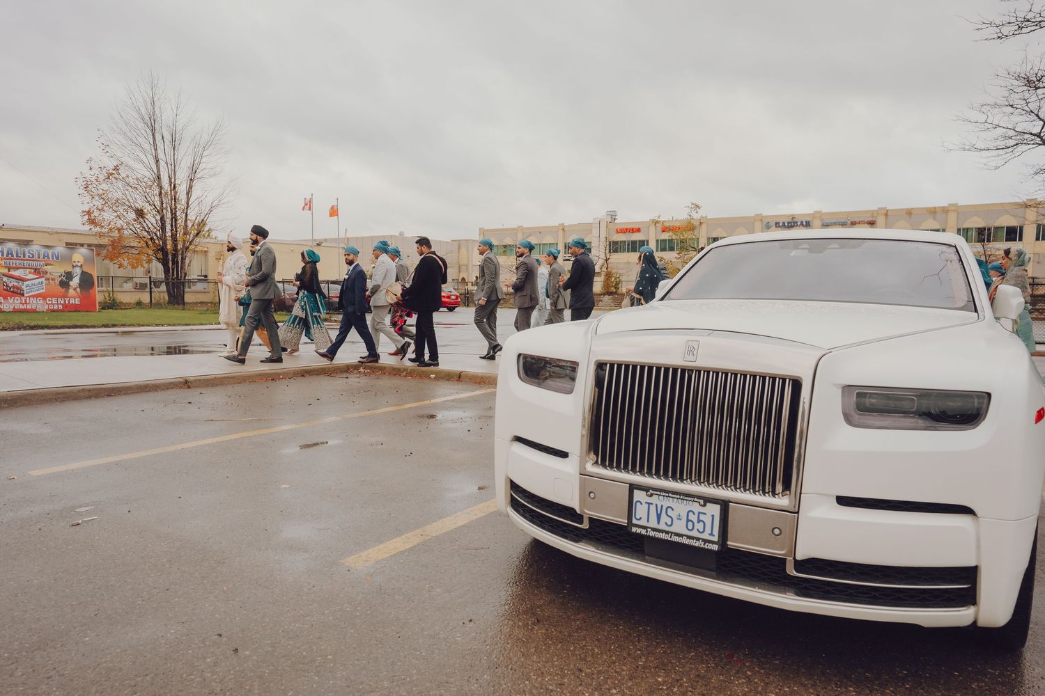 White luxury Rolls Royce vehicles parked in a line on an overcast day.