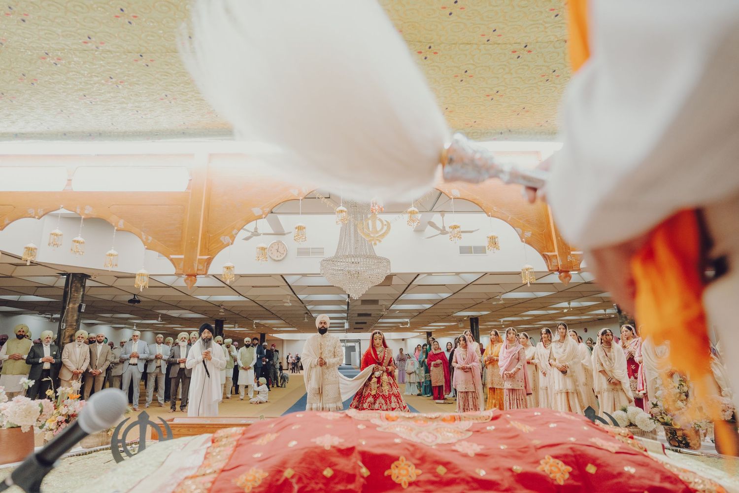 Panoramic view of an indoor wedding reception with white tent canopy and orange accents.