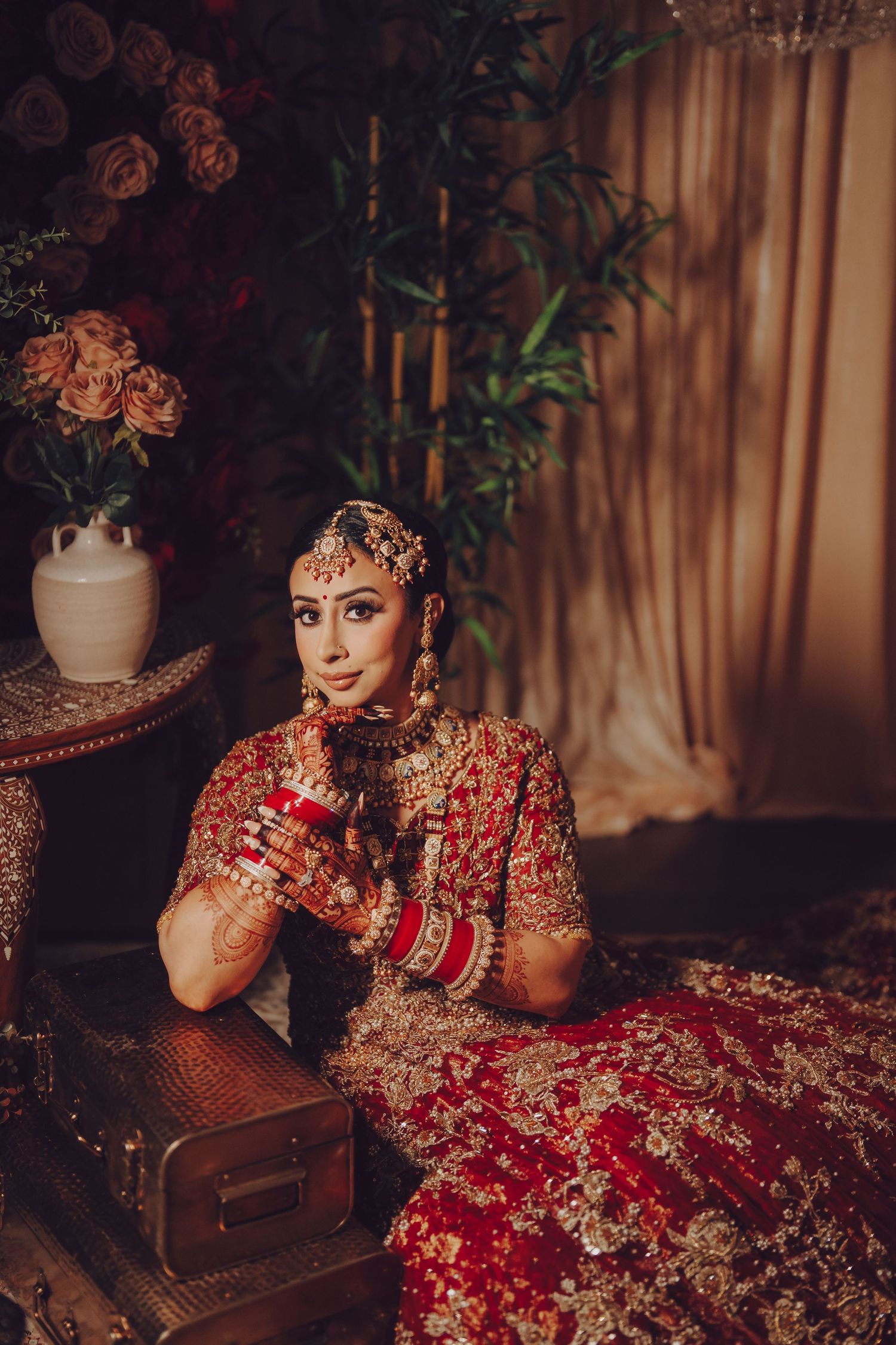 Ornate bridal photography session featuring traditional red and gold South Asian wedding attire.