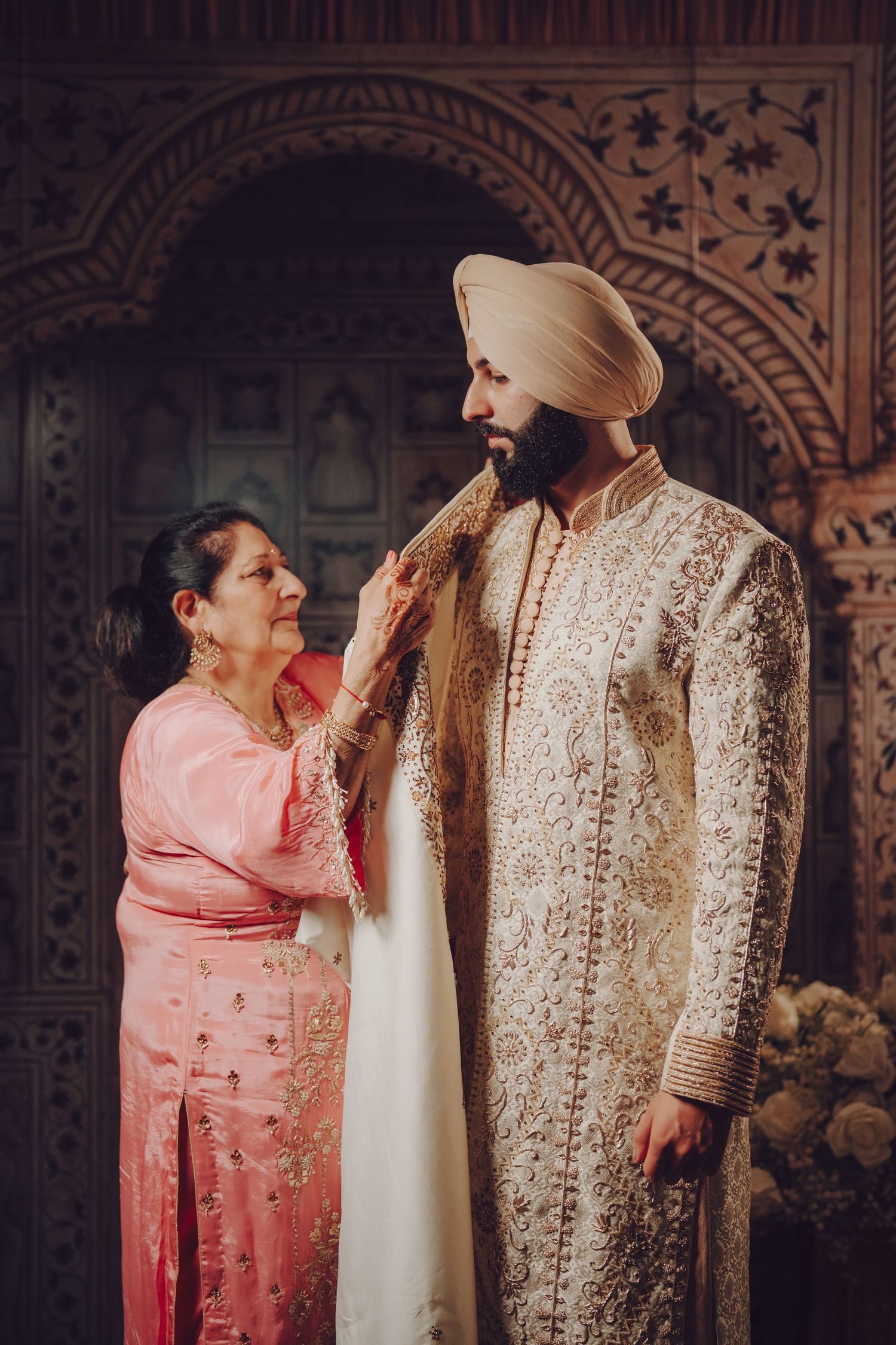 Wedding preparation scene with traditional Sikh ceremonial dress against ornate backdrop.