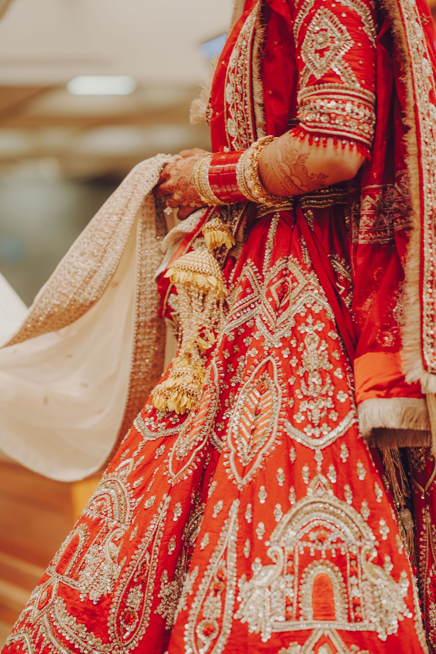 Detail of red and gold embroidered lehenga with intricate traditional Indian bridal designs.