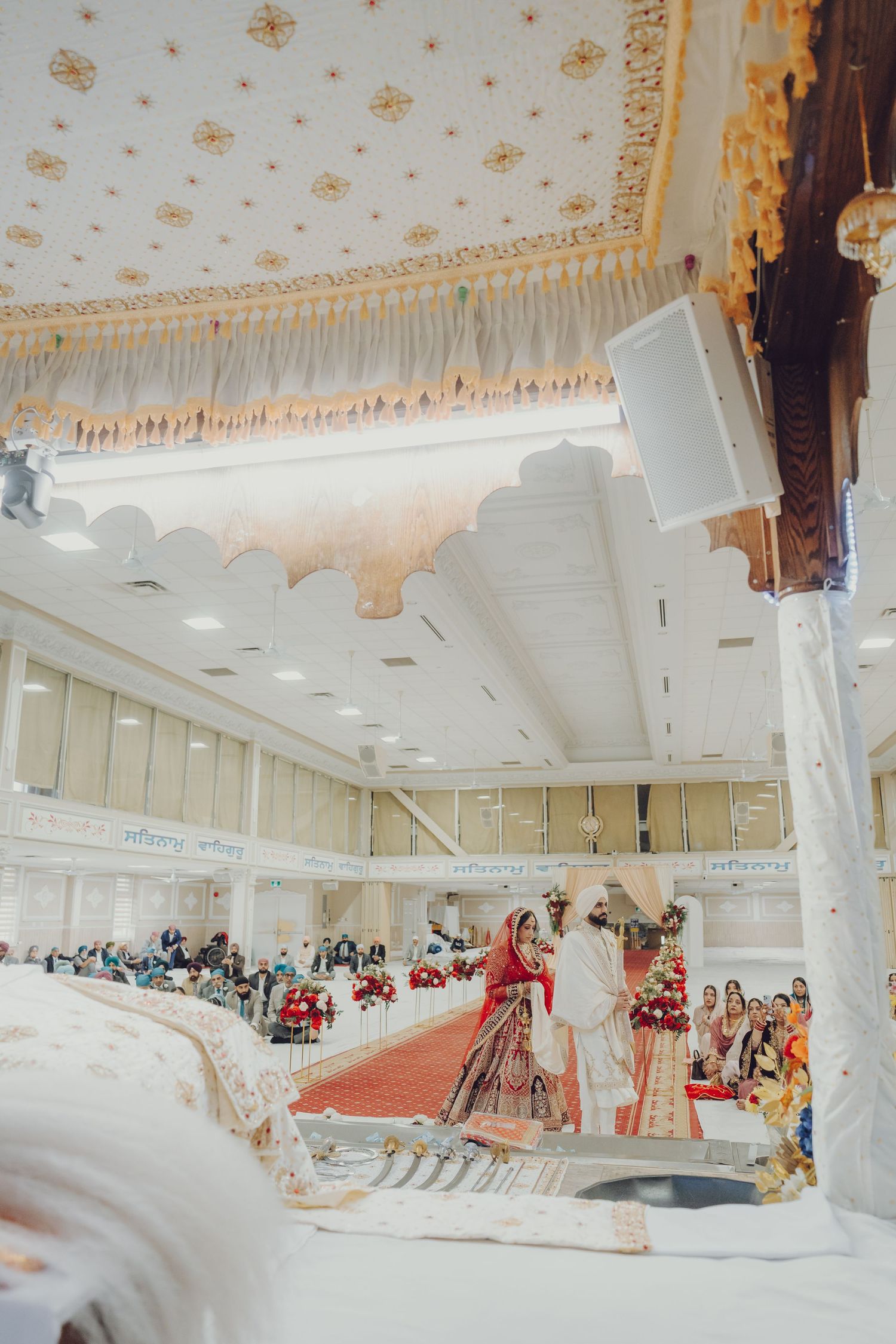 Panoramic shot of a spacious wedding venue with ornate ceiling and traditional Indian ceremony setup.
