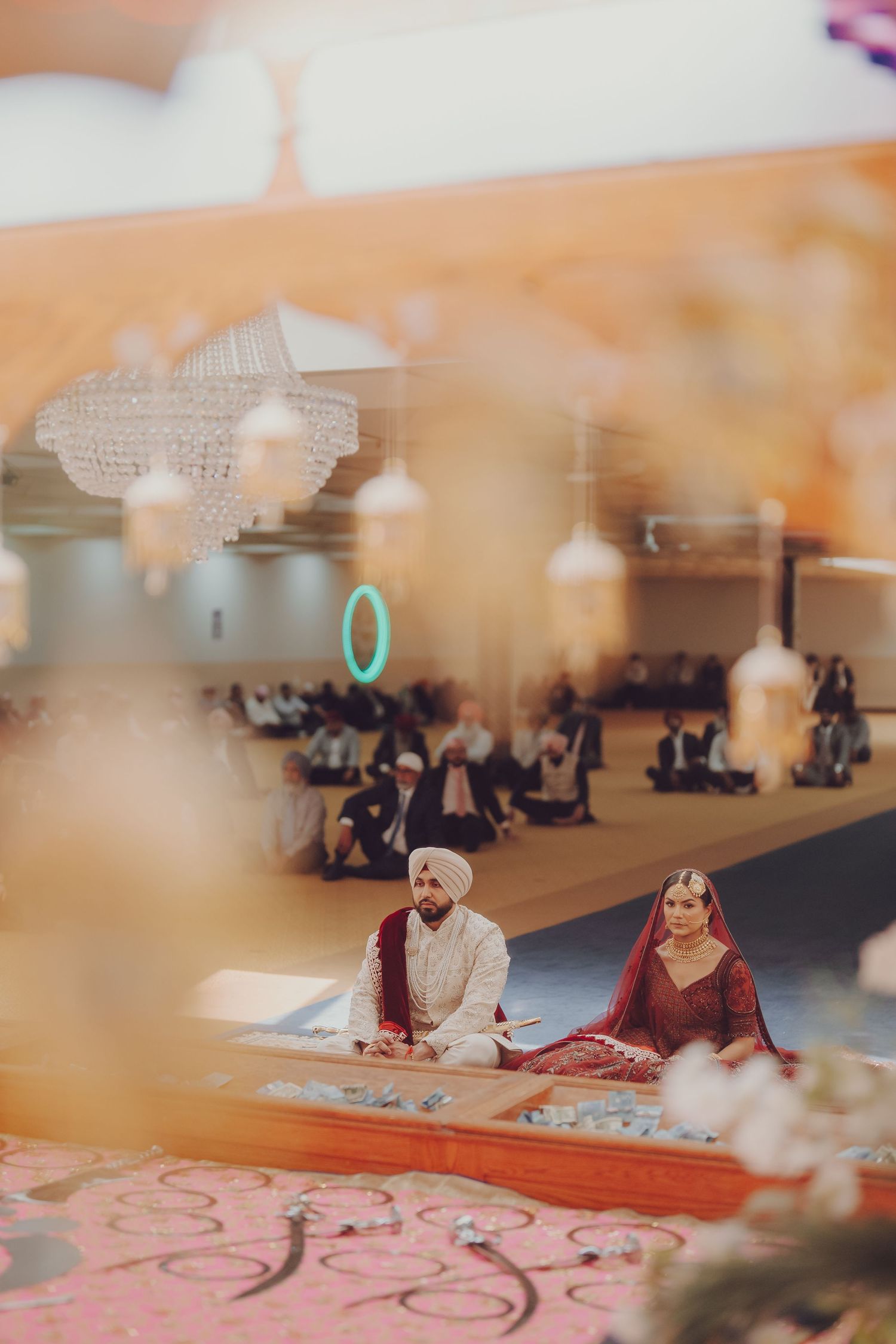 Traditional Sikh wedding ceremony with couple seated on floor during religious proceedings.