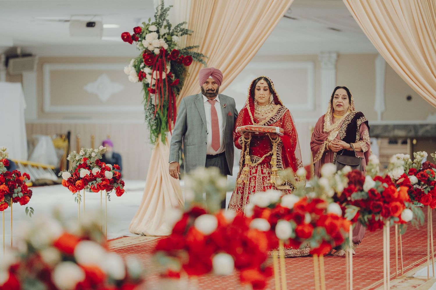 Elegant wedding venue decorated with red roses and cream drapes for traditional ceremony.