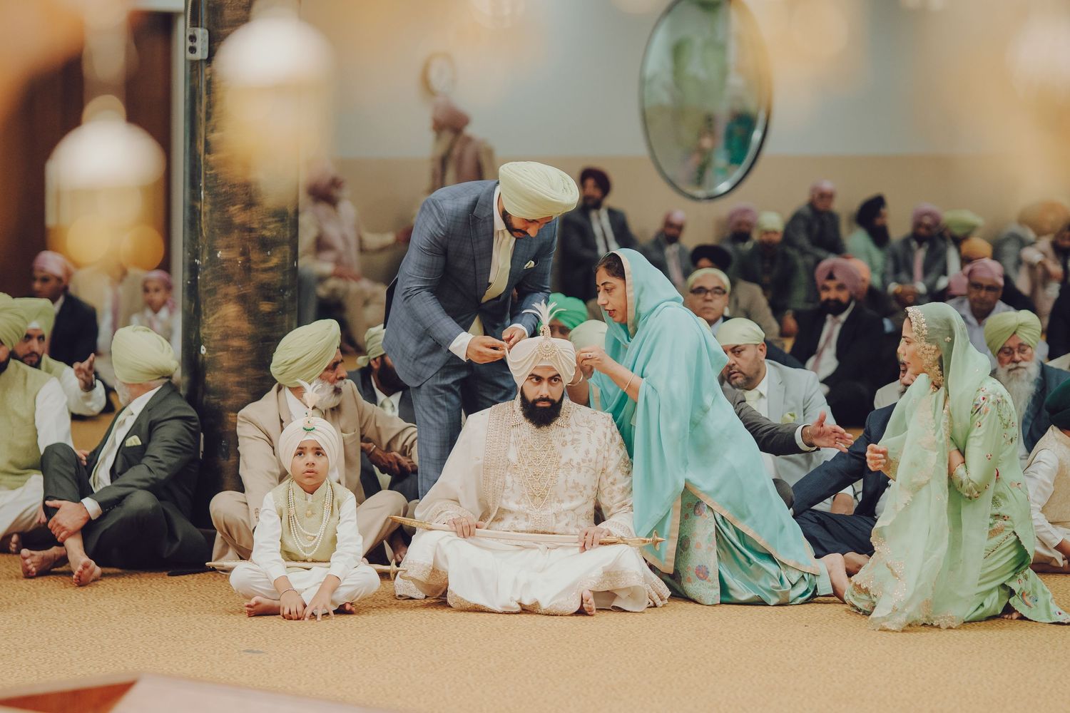 A row of wedding guests in traditional Middle Eastern attire seated on the floor during a cultural celebration.