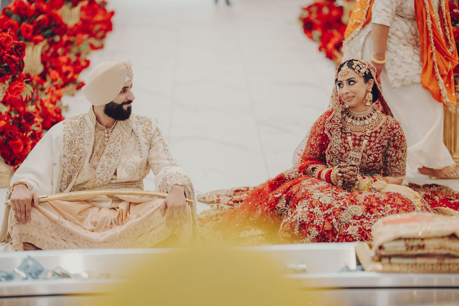 A traditional Indian wedding ceremony with decorative red and gold floral arrangements and cultural attire.