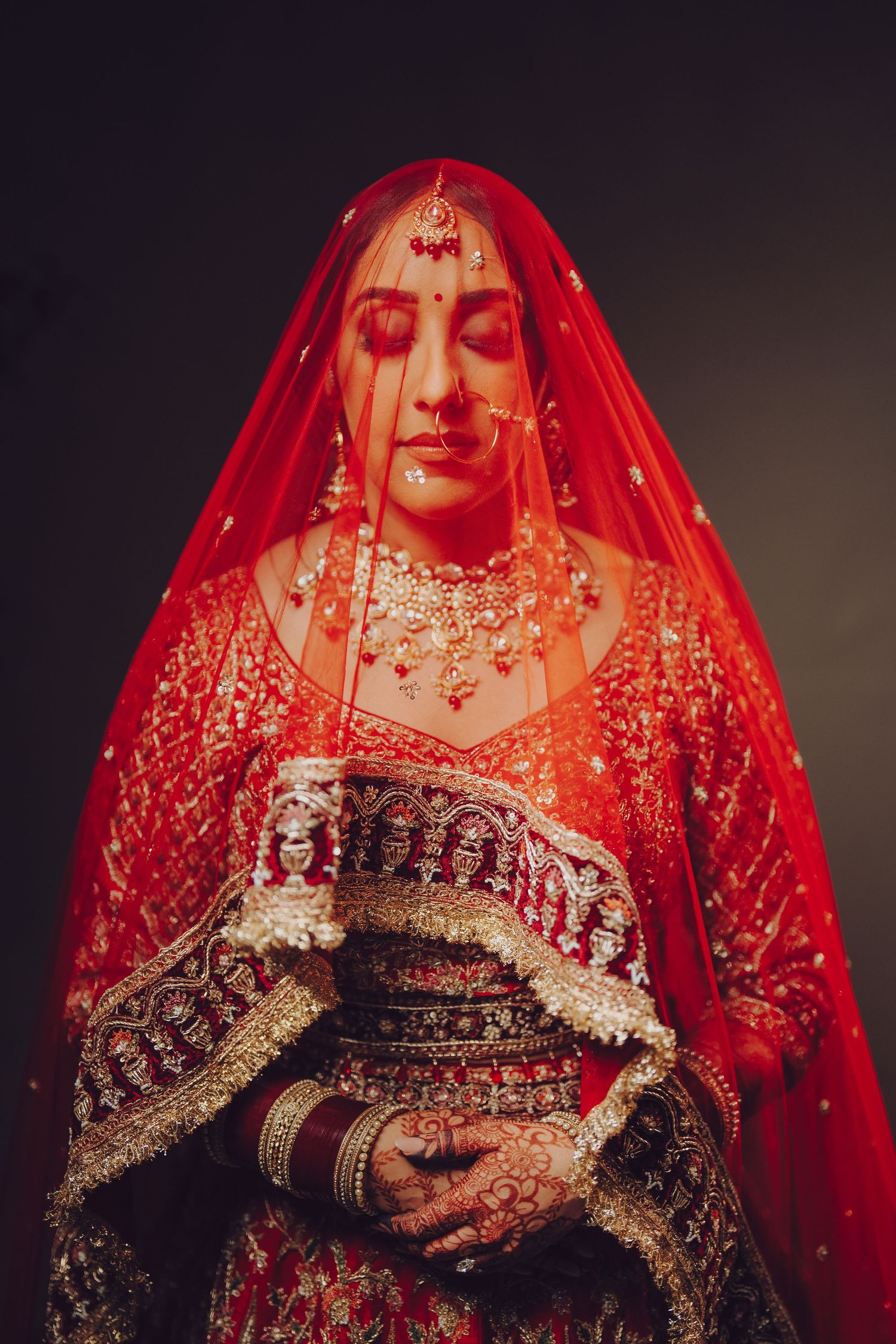 Traditional Indian bride wearing an ornate red wedding lehenga with intricate embroidery and embellishments.