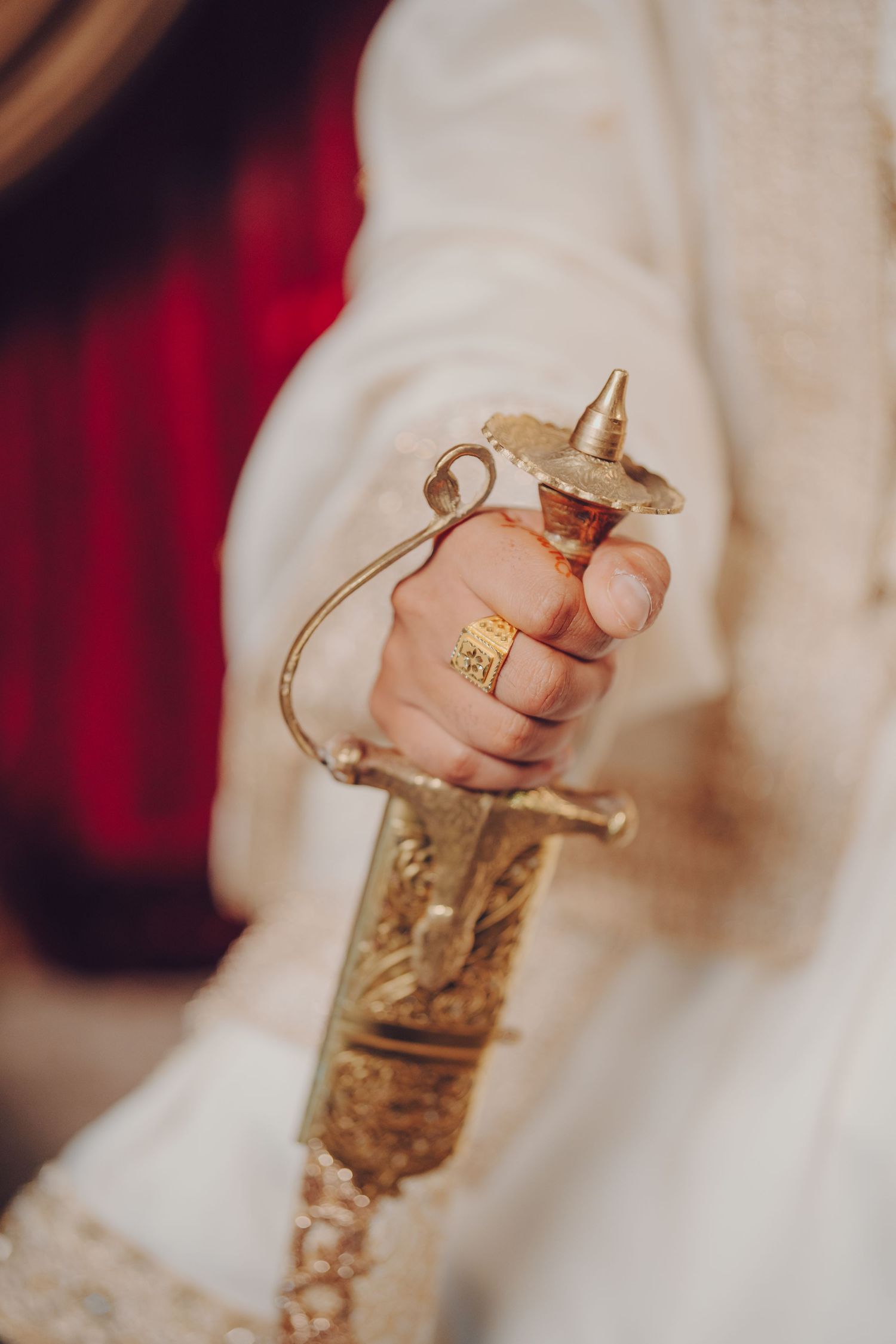 Close-up shot of a decorative golden ceremonial sword handle held against a white fabric.