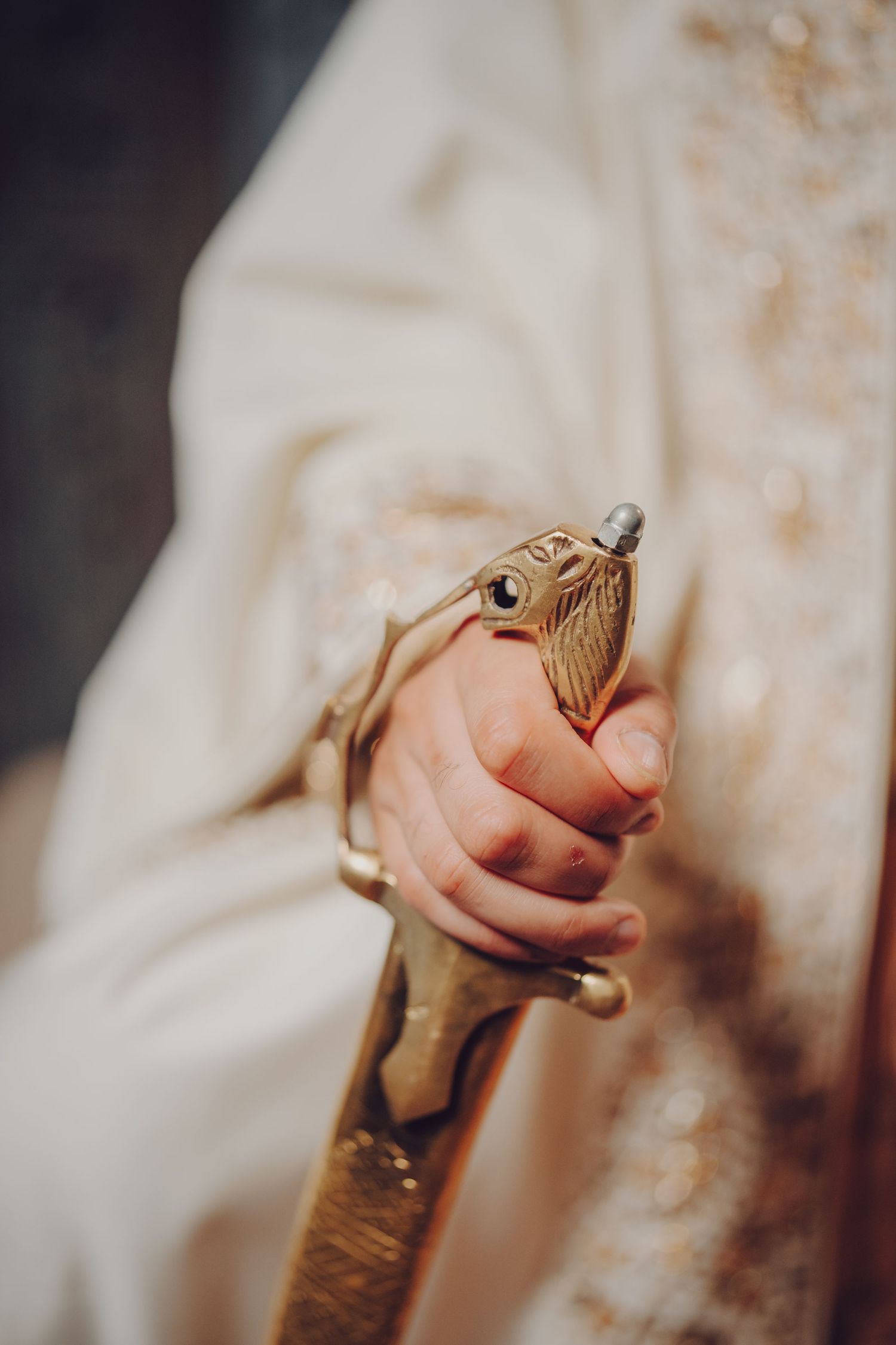 Close-up shot of hands holding a ceremonial sword with ornate gold handle.