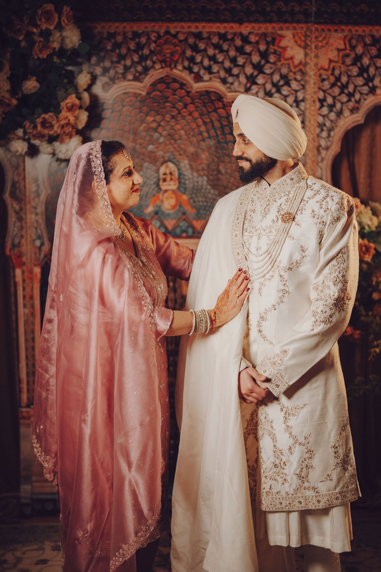 Wedding ceremony moment showing traditional Indian outfits in pink and white with detailed embroidery.