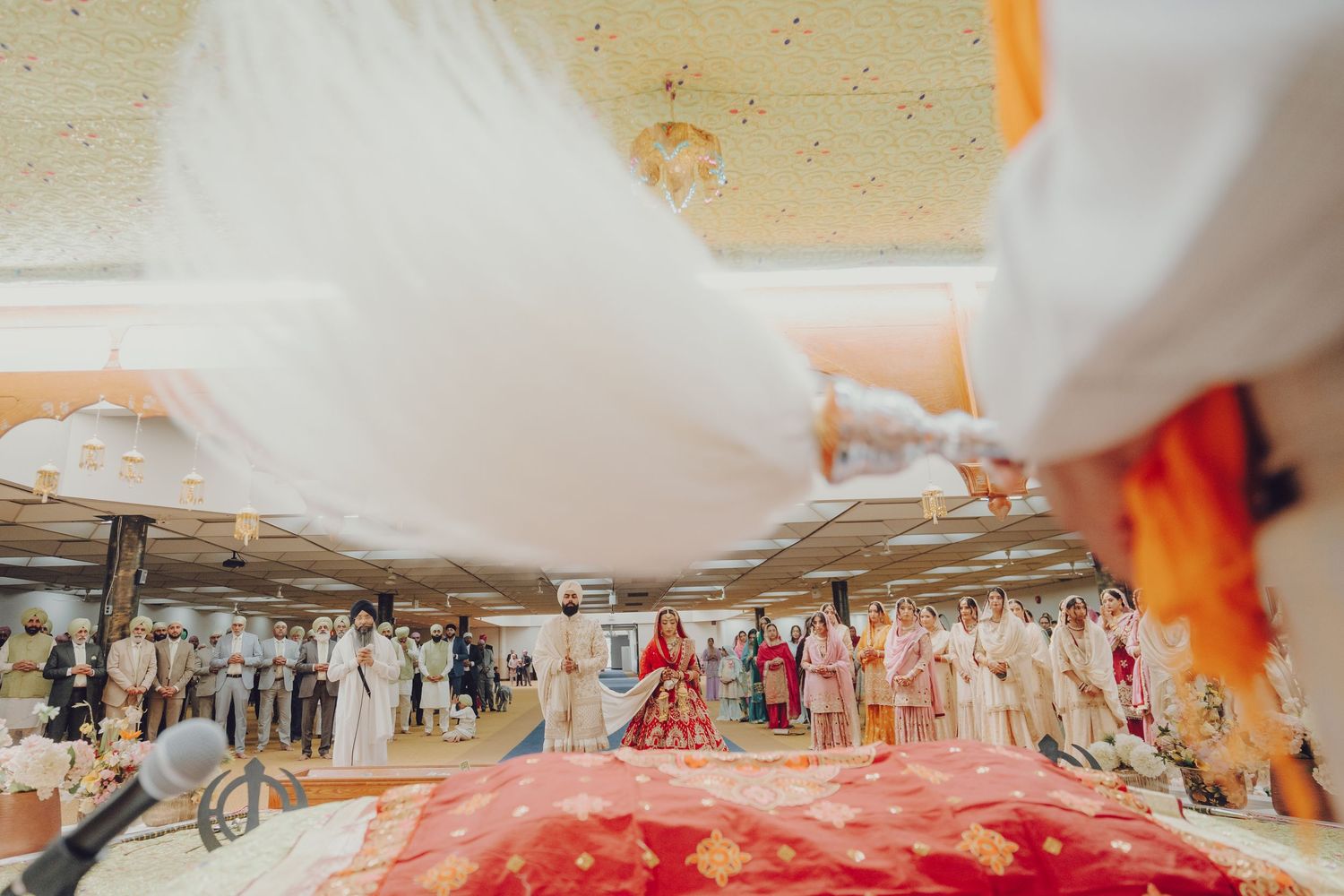 Wide angle view of a wedding venue with white drapes and guests seated in rows.