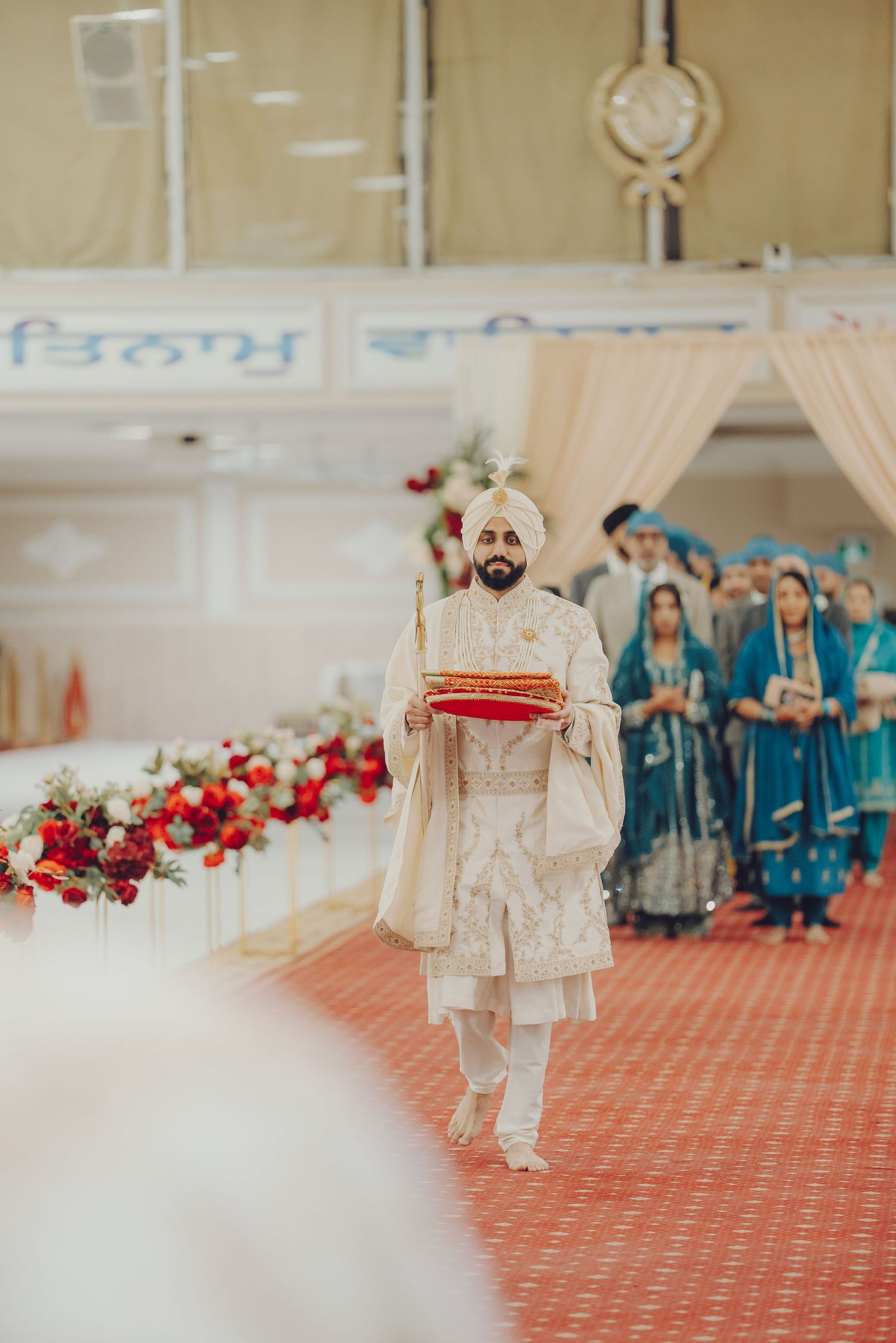 Sikh wedding ceremony with guests in traditional attire and floral decorations.