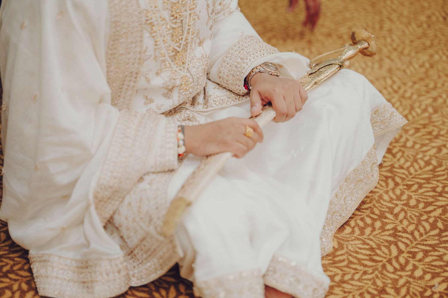 Close-up details of traditional white wedding attire with delicate embroidery patterns.