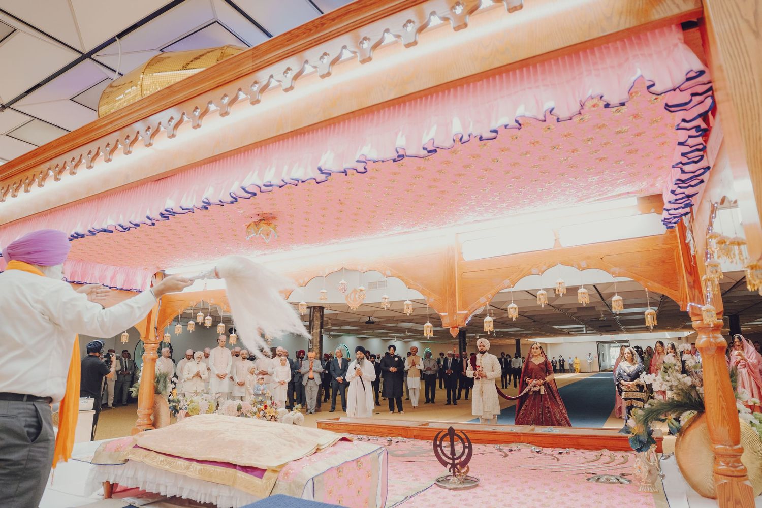 Wedding venue decorated with pink and white drapes and traditional Indian elements.