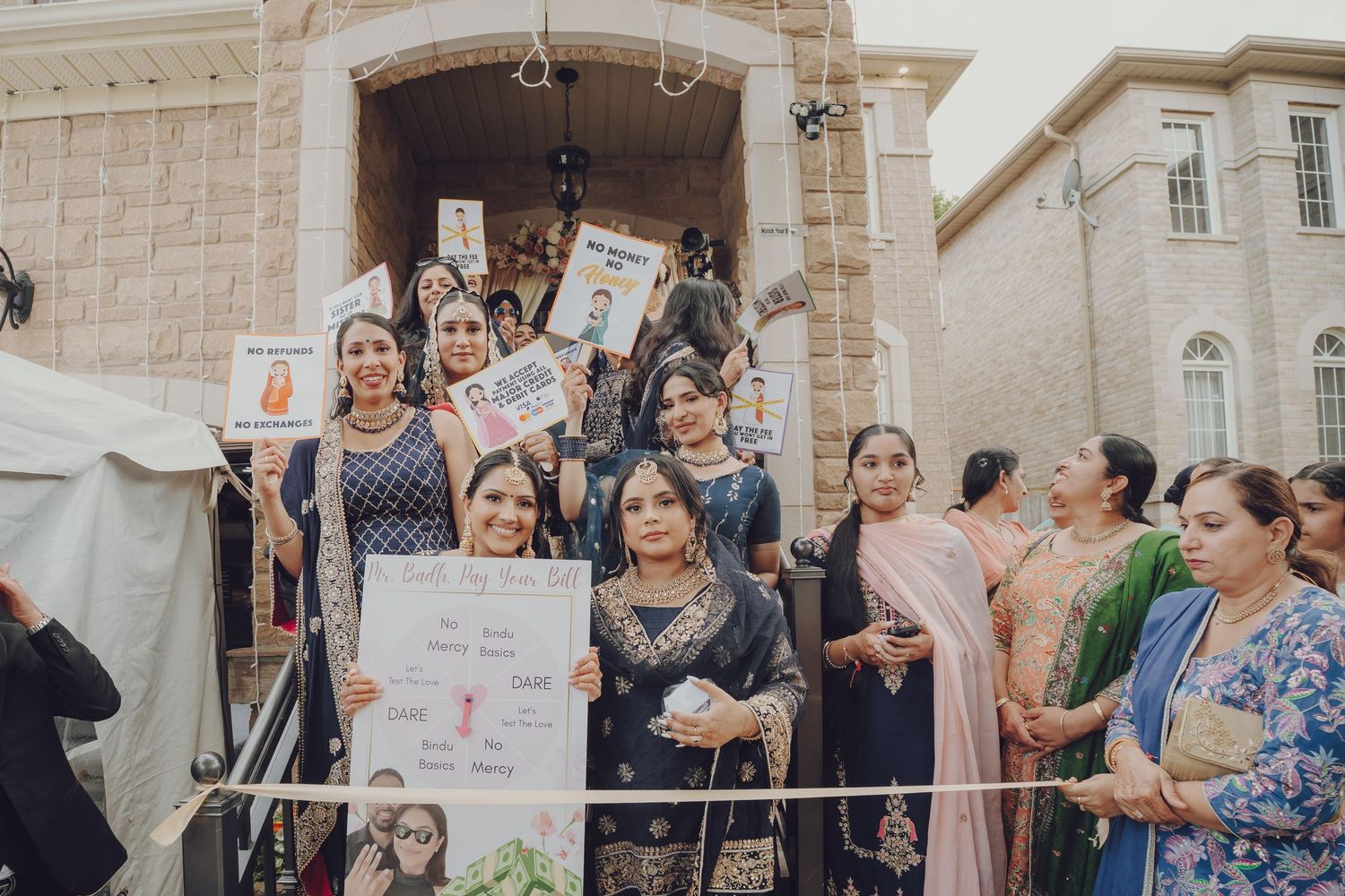 Group celebration outside stone building with guests holding signs and banners.
