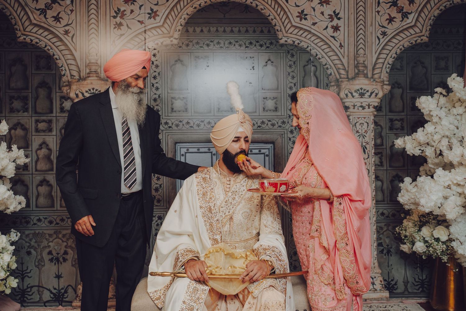 Traditional Sikh wedding ceremony moment with cultural customs and decorative backdrop.