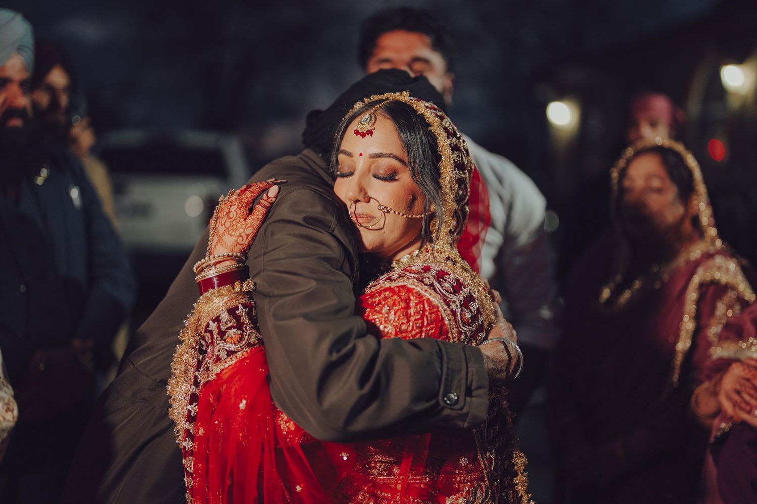 Emotional moments captured during evening wedding celebrations with dark dramatic lighting.