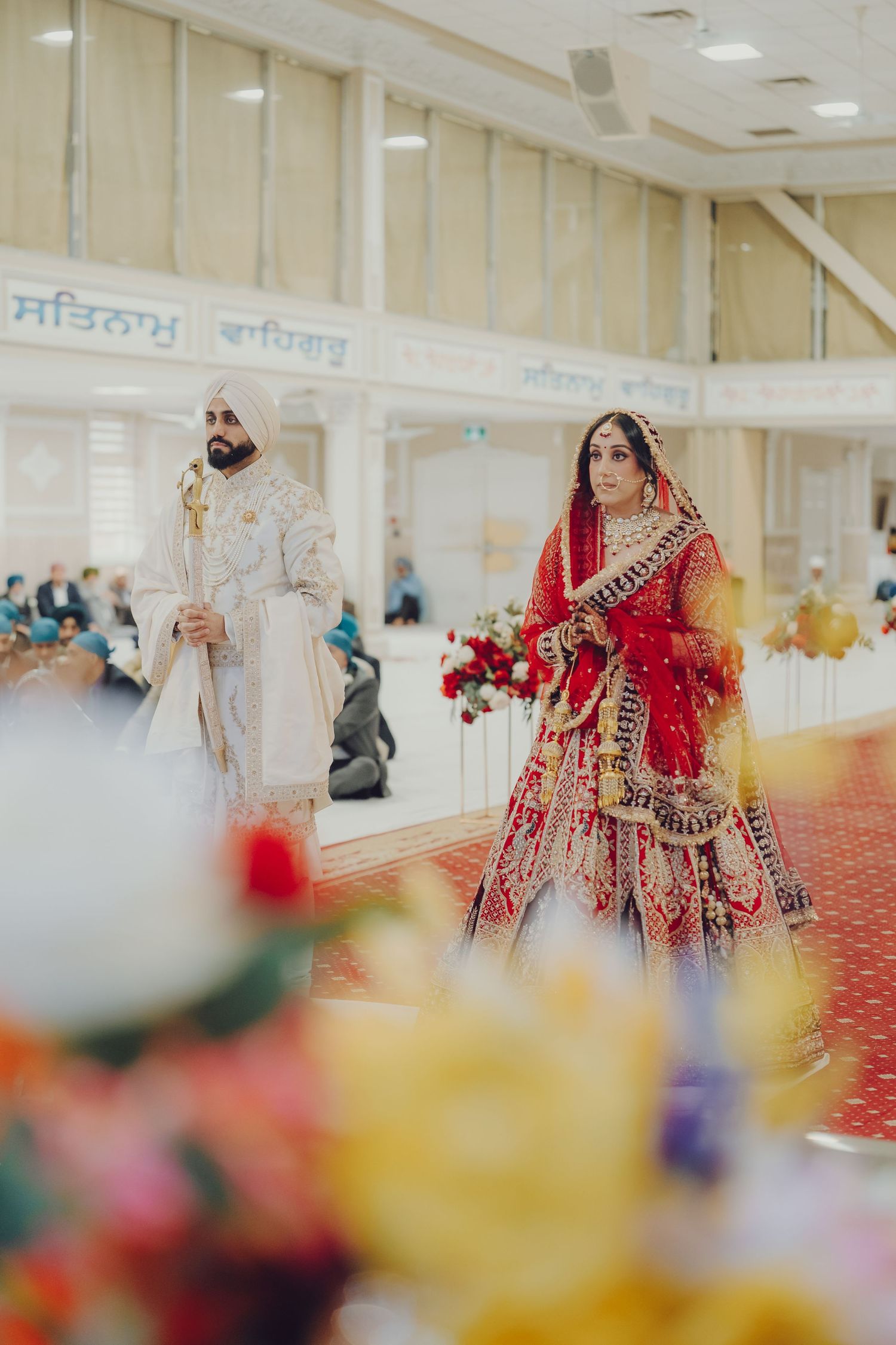 Wide angle view of a Sikh wedding ceremony in a traditional Gurdwara with colorful decorations.