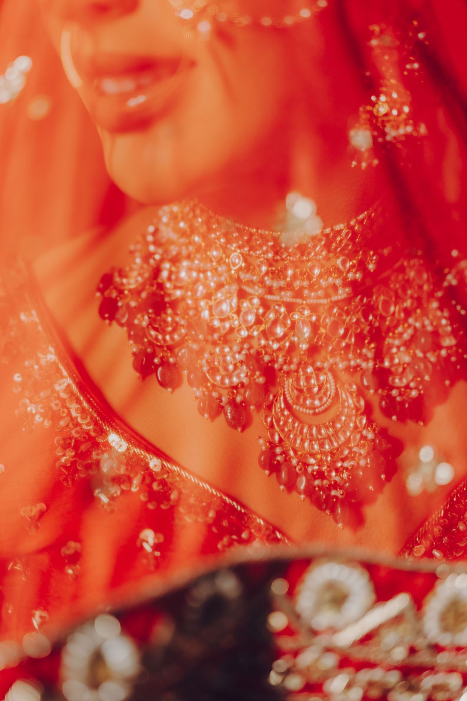 Close-up detail of red and gold beaded jewelry with intricate traditional Indian design patterns.