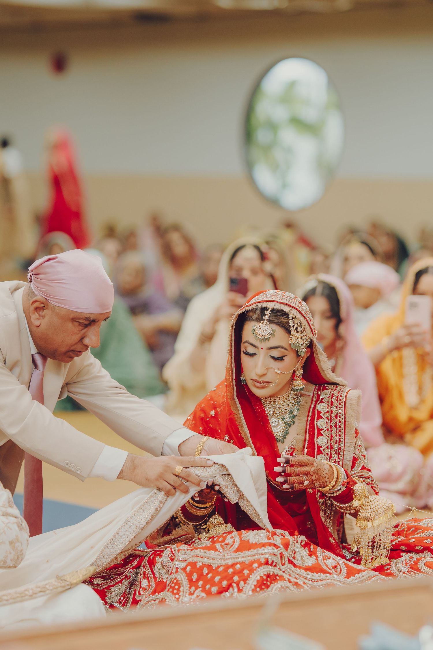 Traditional Sikh wedding ceremony taking place with guests gathered around in a prayer hall.