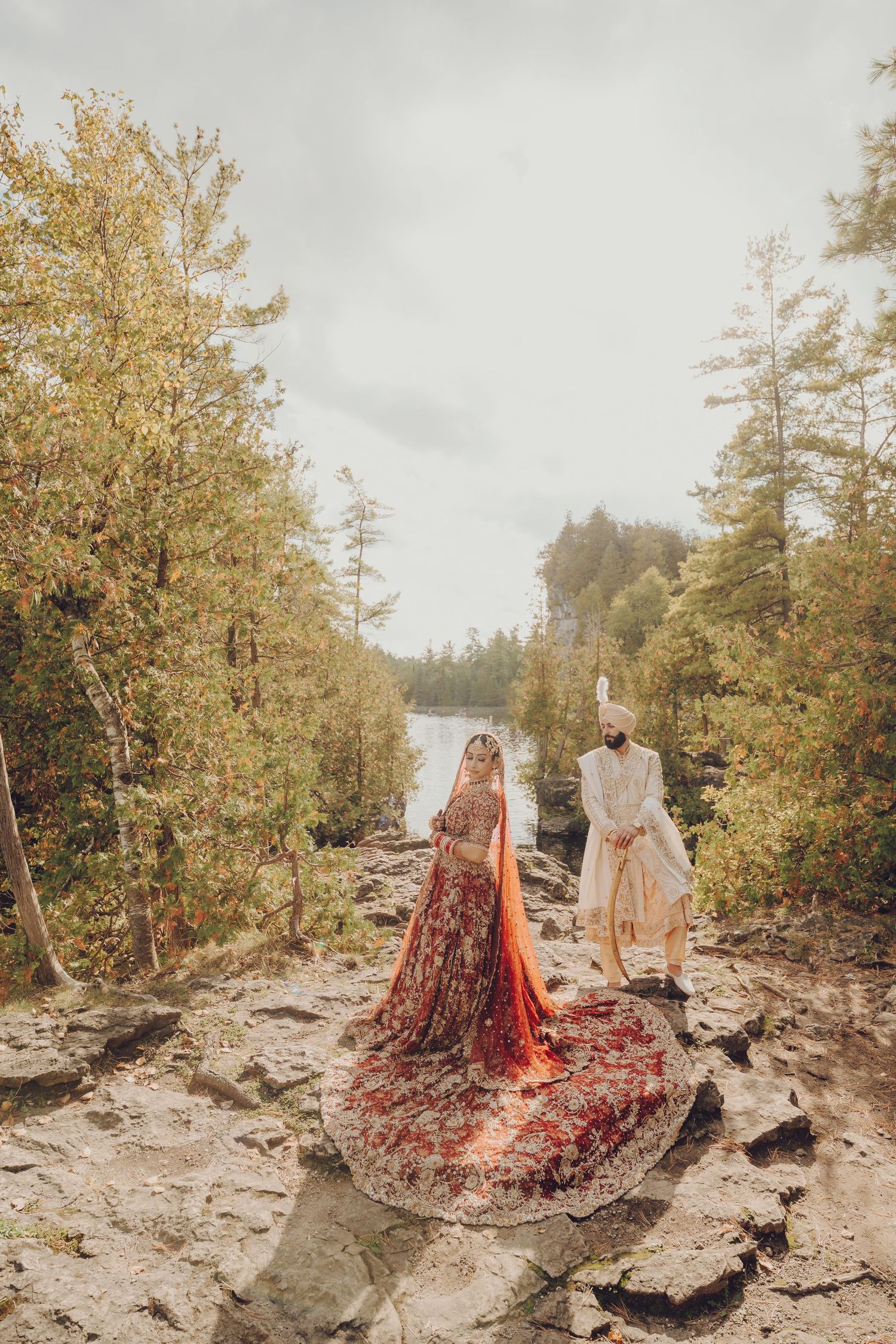 Wedding ceremony setup on rocky terrain with red fabric and natural lakeside backdrop.