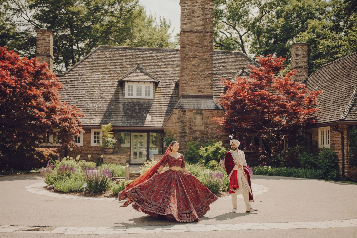 Wedding couple in traditional attire posing for photos outside a stone building.