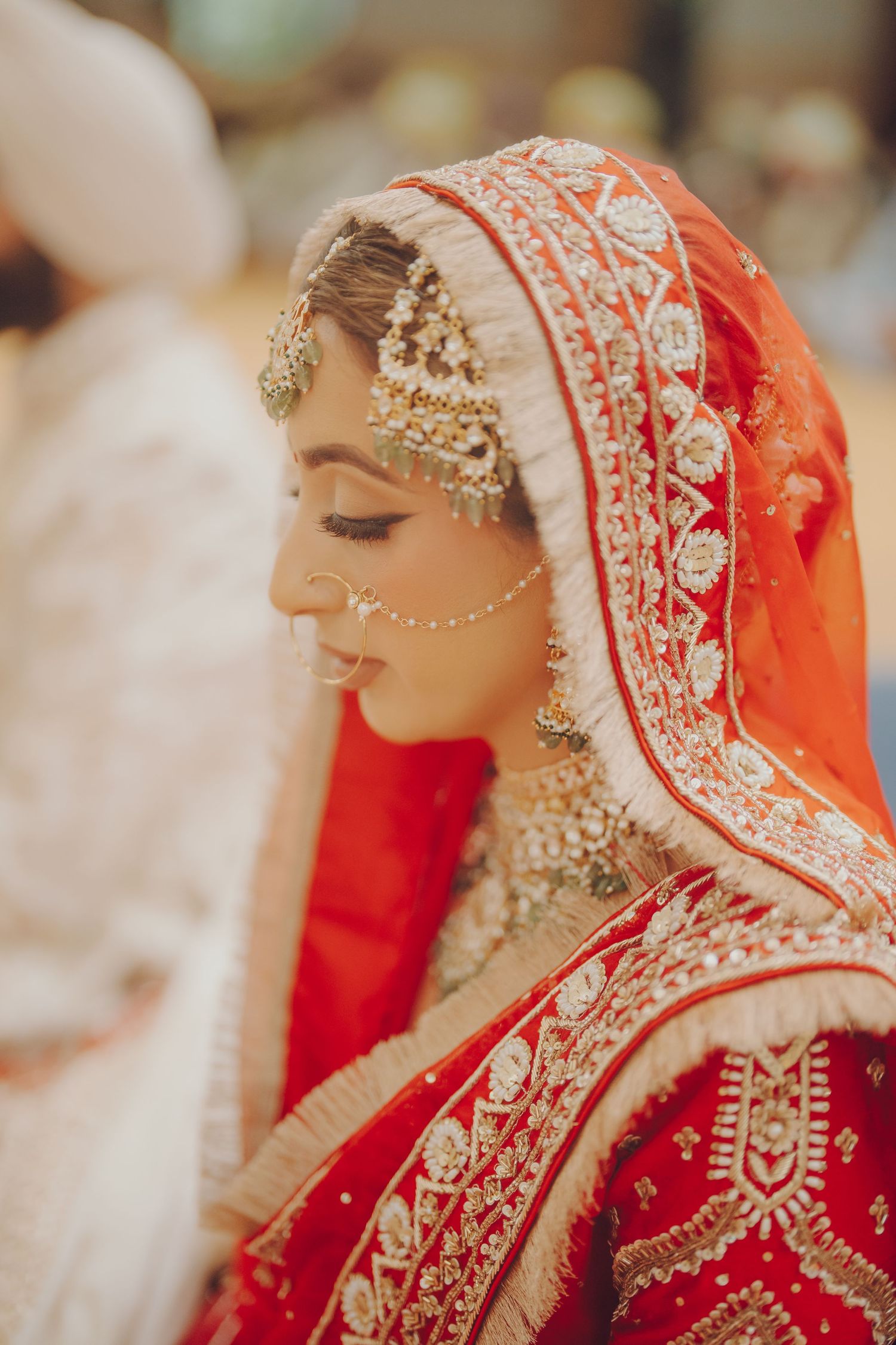 Traditional Indian bridal attire featuring intricate embroidery and a vibrant red dupatta with gold embellishments.