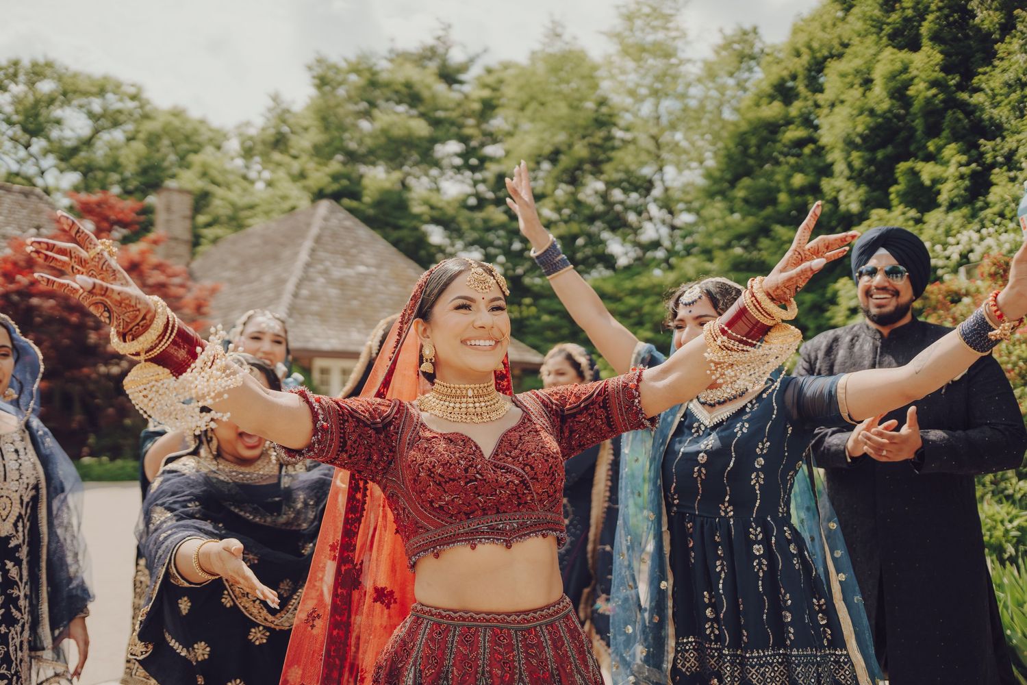 Celebratory dance at outdoor Indian wedding with guests in colorful attire.