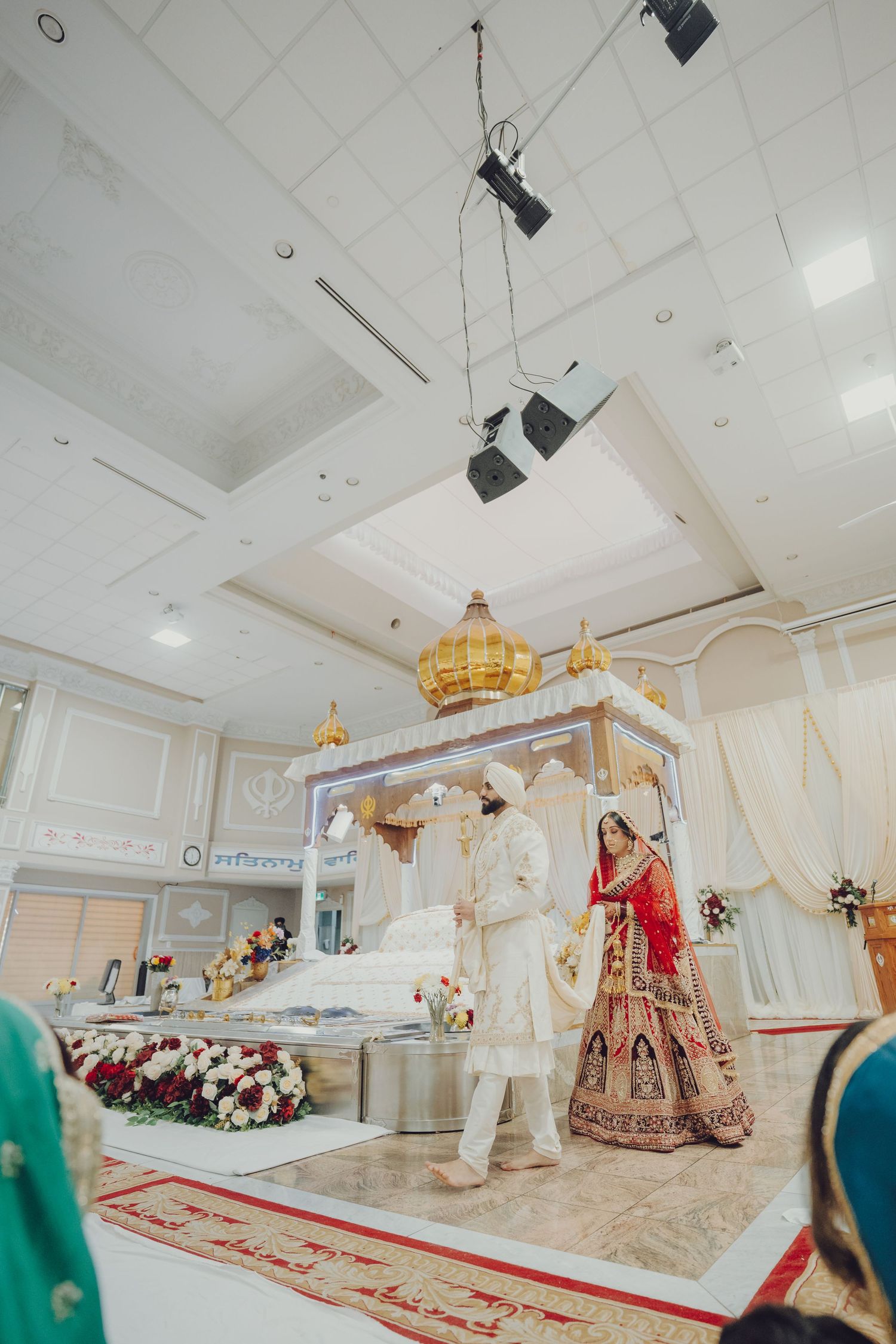 Sikh wedding ceremony in progress under chandelier in modern temple hall.