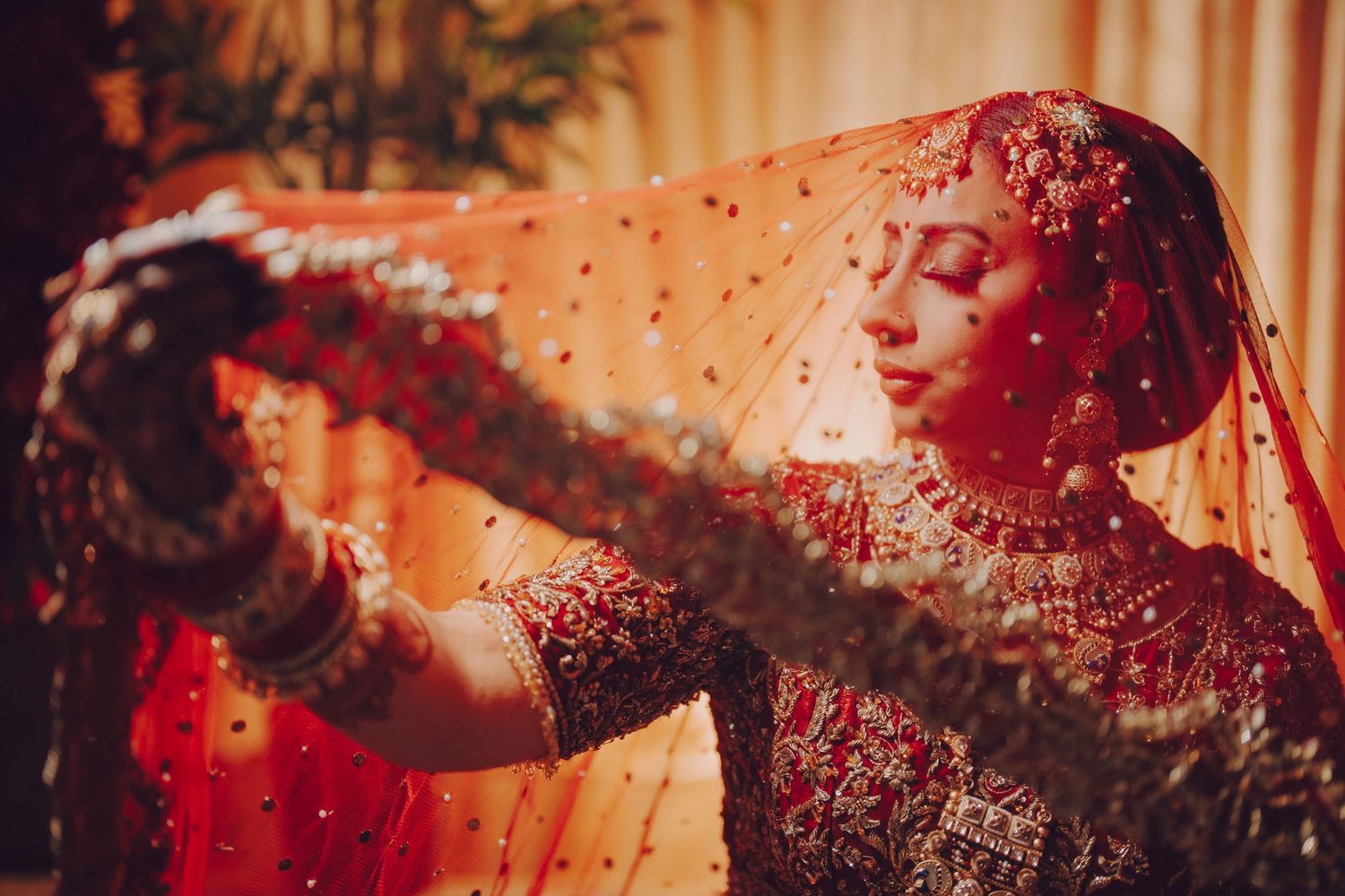 Artistic close-up of detailed red and gold embroidered Indian wedding attire.