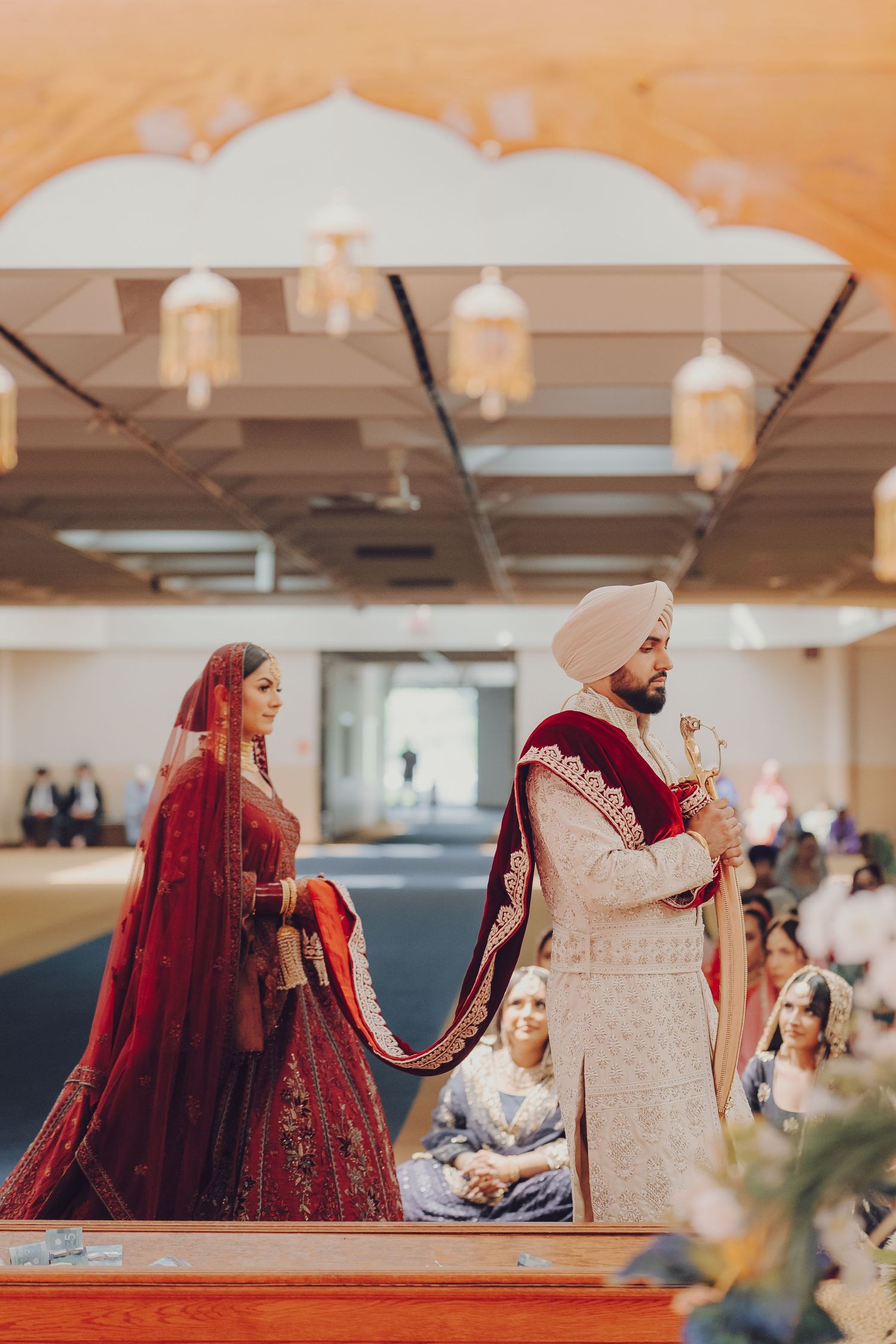 Sikh wedding ceremony showing couple during traditional rituals in indoor venue.