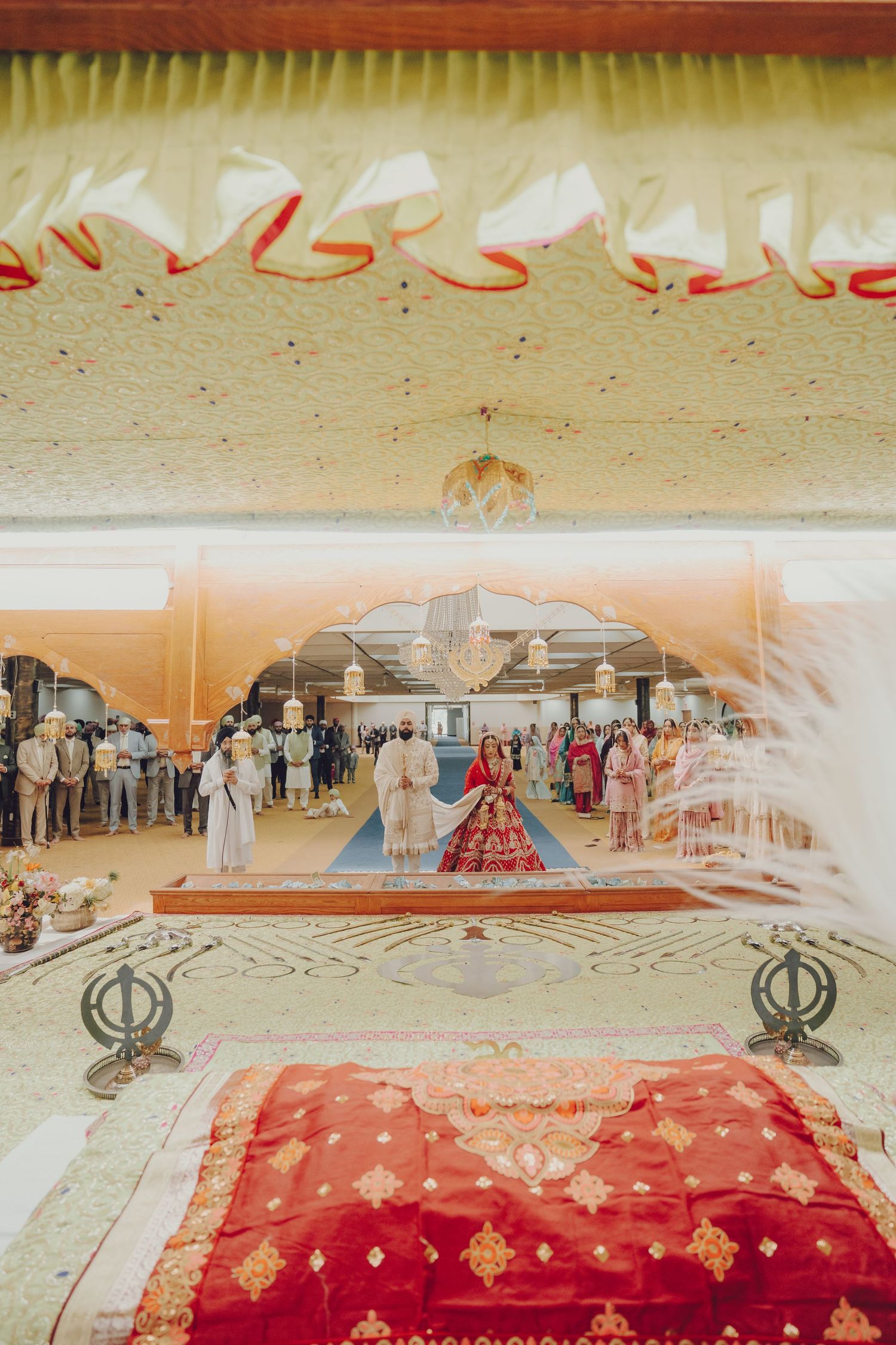 Wide view of a traditional Sikh wedding ceremony setup with red carpet and decorative elements.