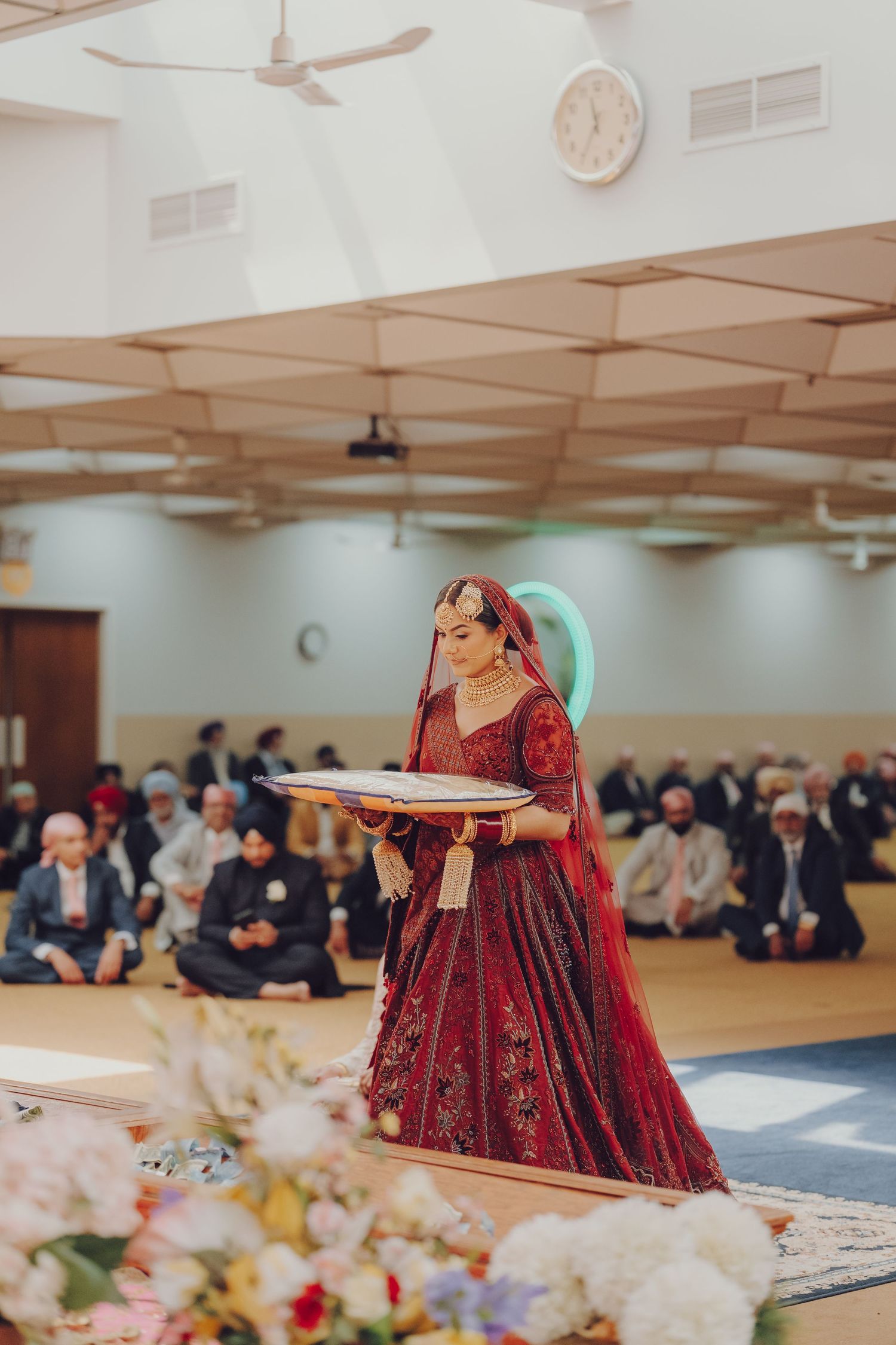 Traditional Sikh wedding ceremony in progress with guests seated and bride in burgundy attire.