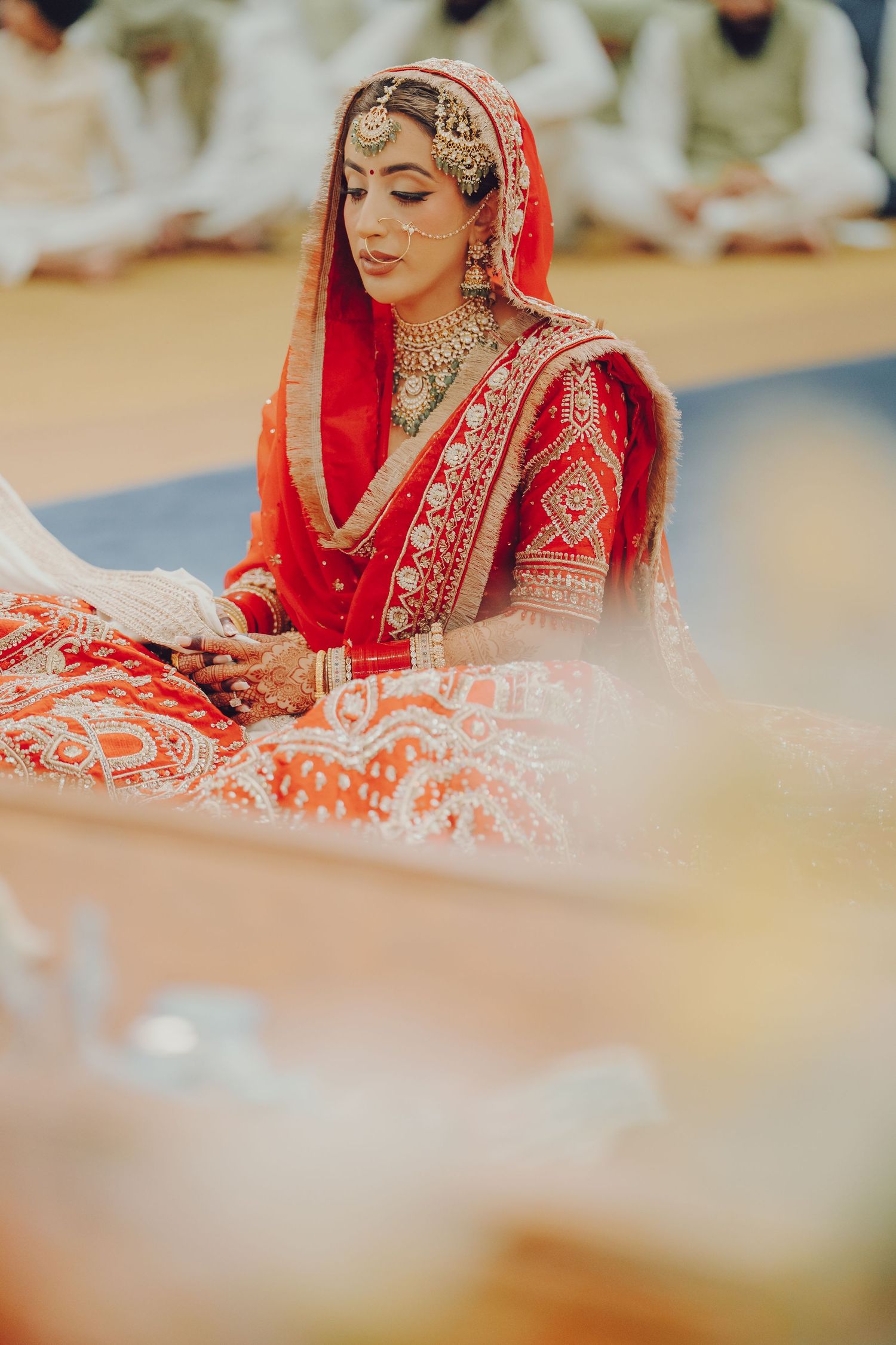 Traditional Indian bride in red and gold bridal attire during wedding ceremony.