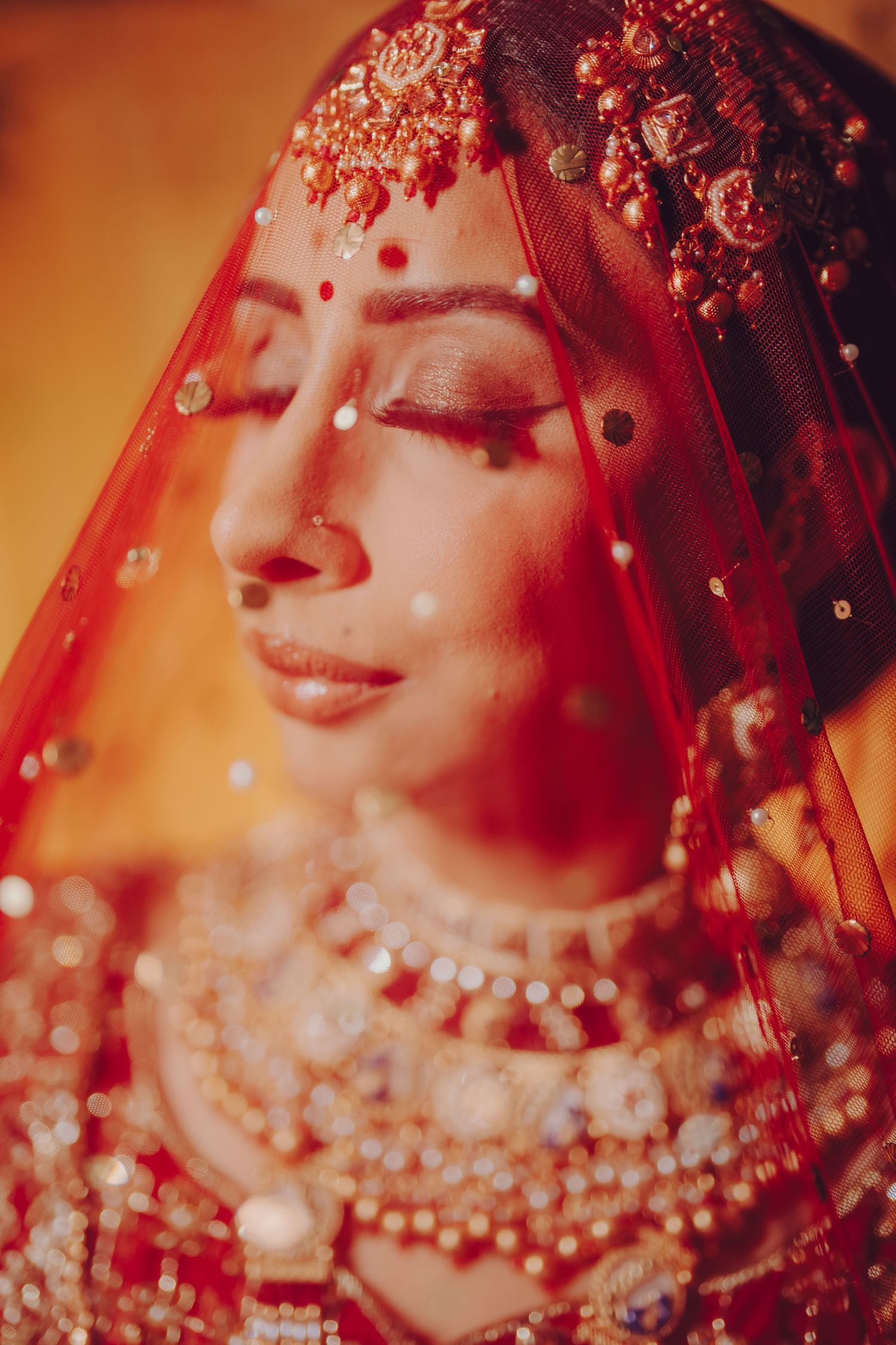 Close-up details of traditional South Asian bridal jewelry and attire in rich red and gold colors.