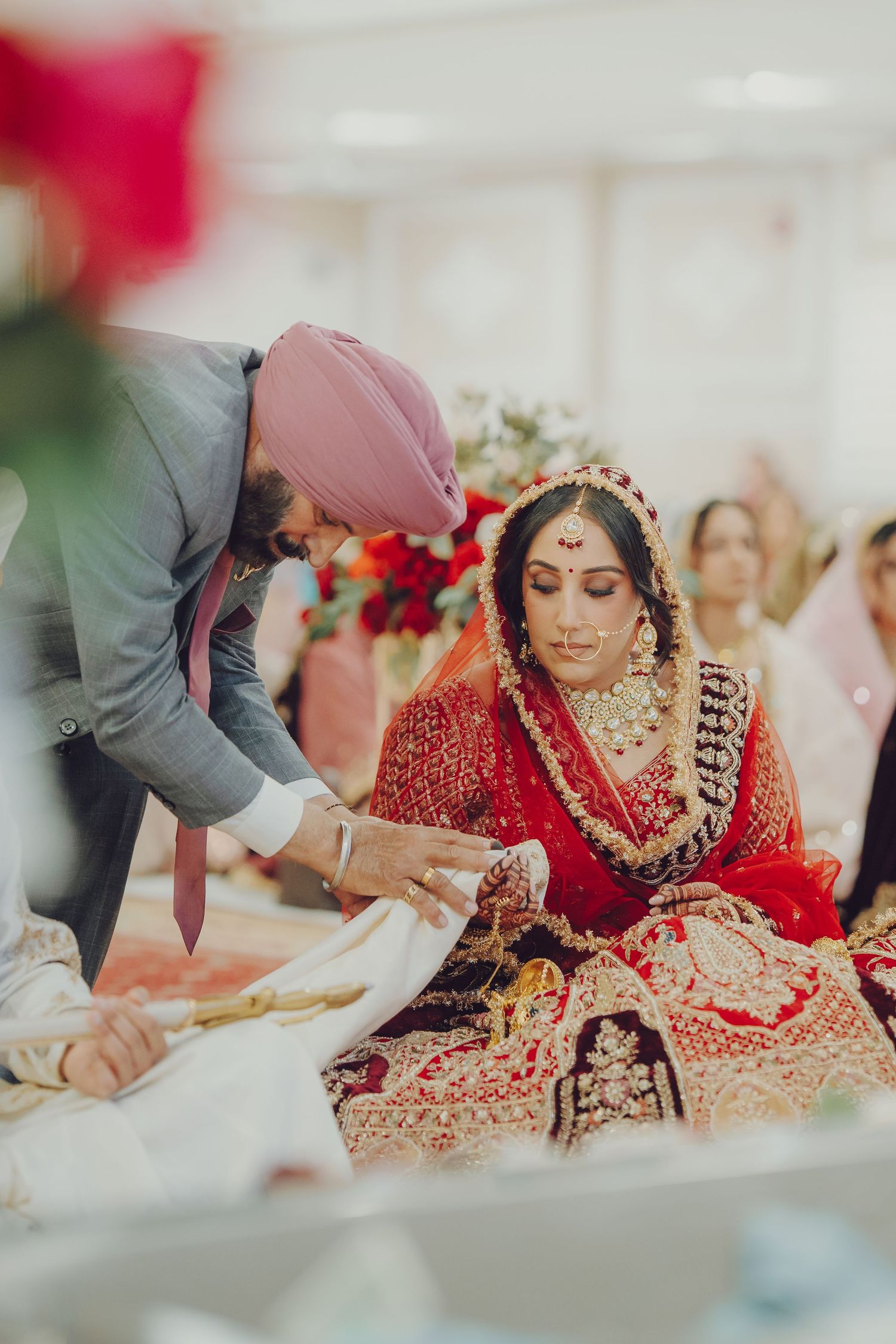 Traditional Indian wedding ceremony showing bride in ornate red lehenga and gold jewelry during ritual customs.