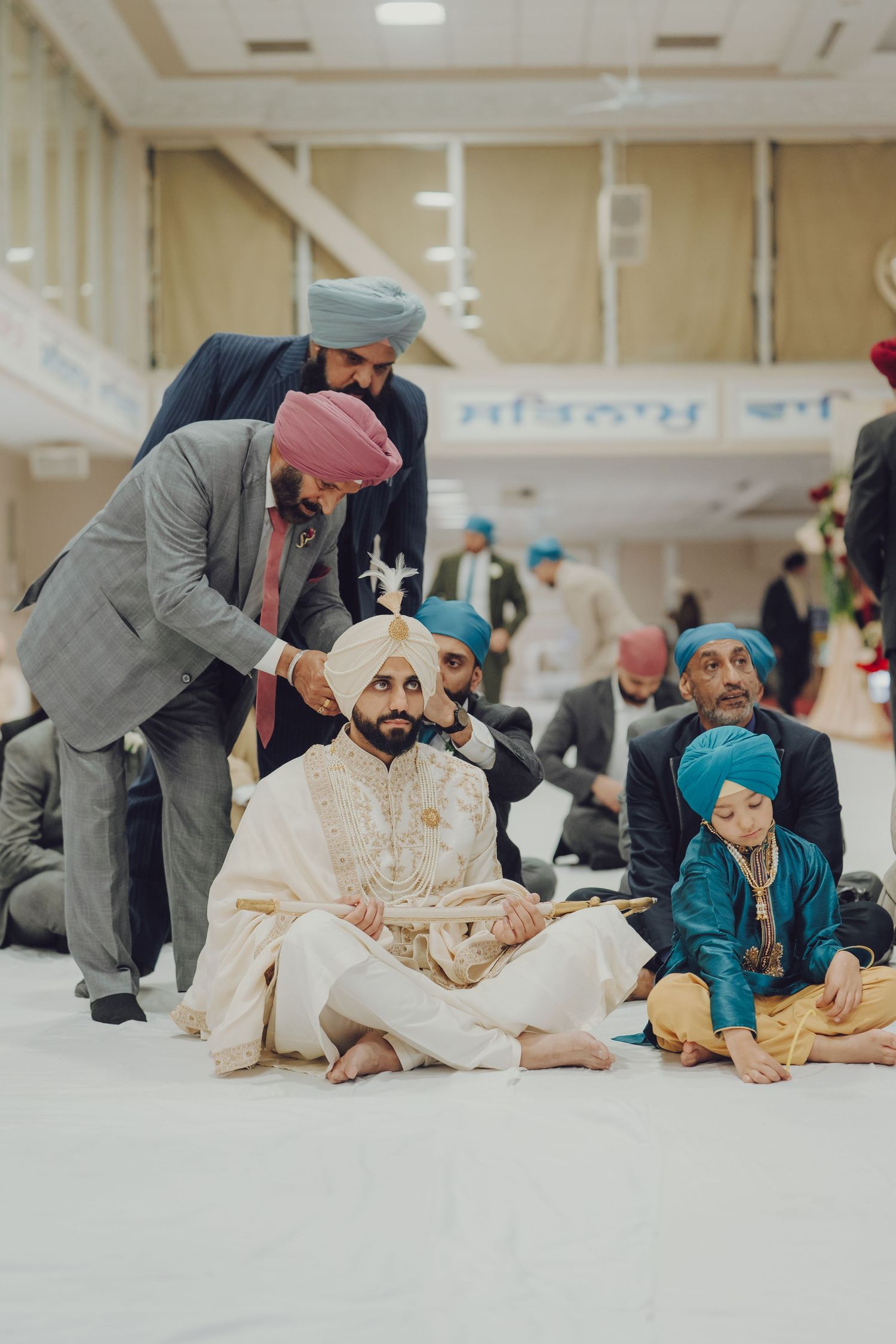 Traditional Sikh wedding ceremony with guests gathered in a temple hall.