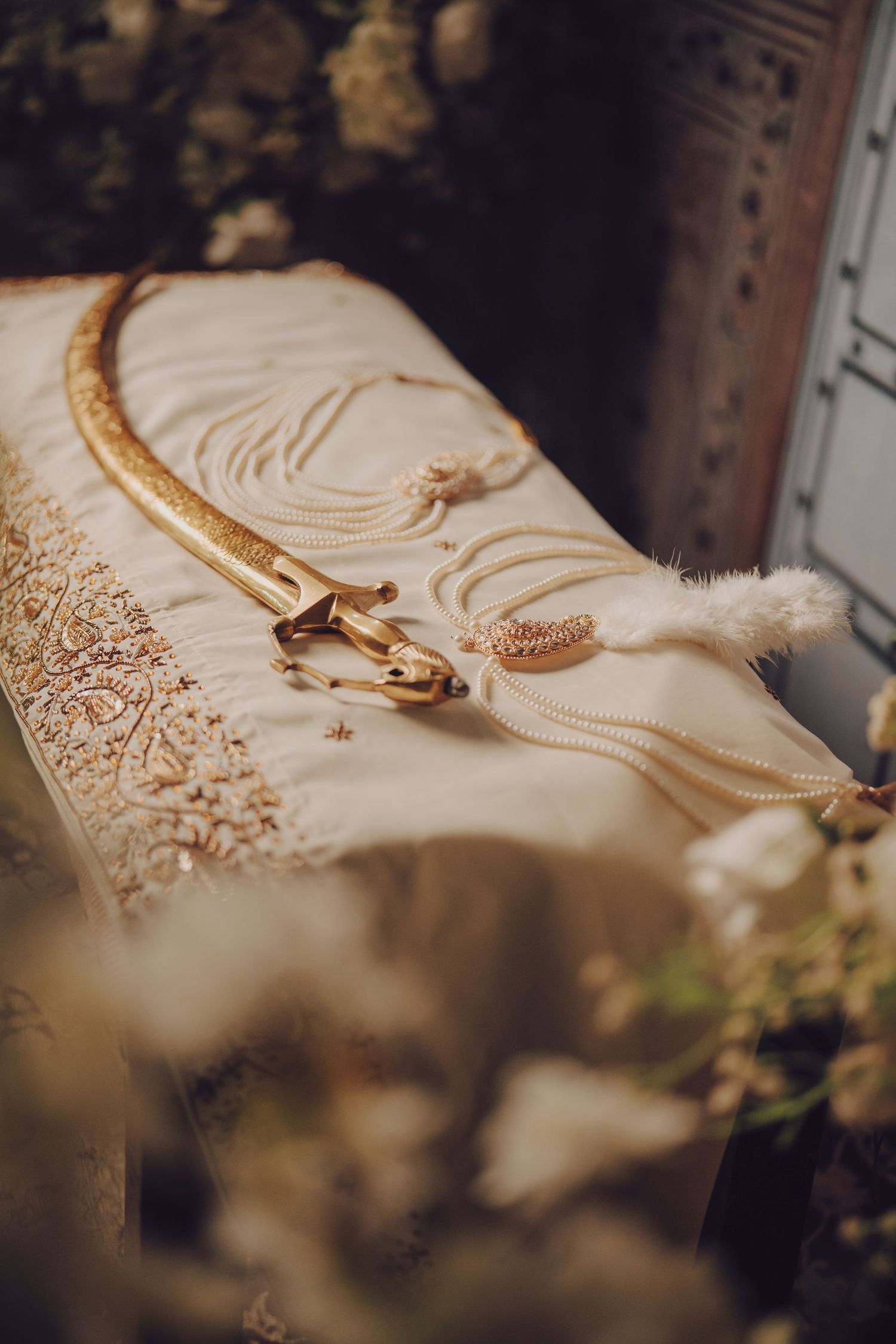 Ornate gold embroidered details on cream colored fabric with decorative elements.