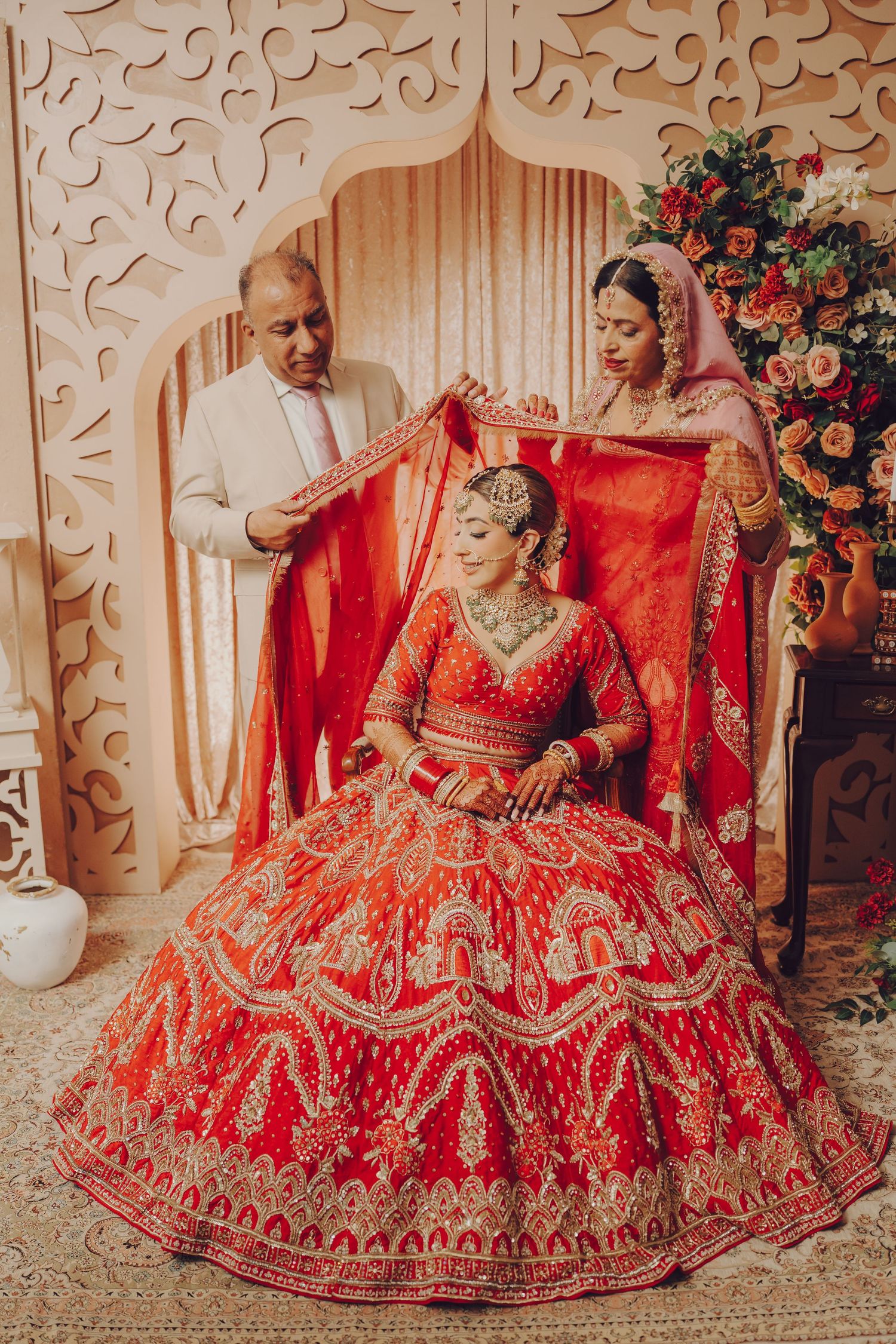 Elegant red bridal lehenga with intricate gold embroidery displayed in a decorative setting.