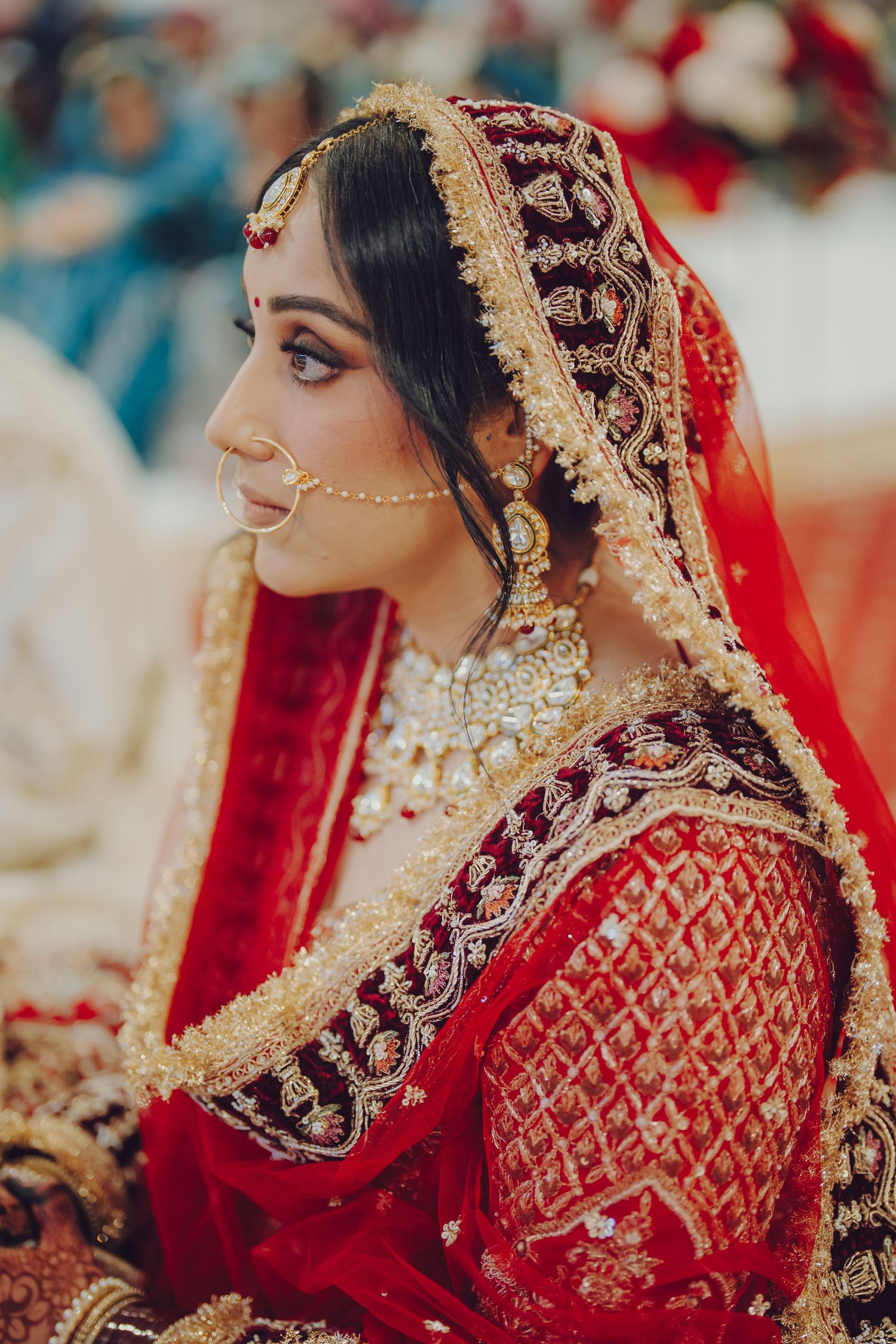 Traditional Indian bride in heavily embroidered red lehenga with gold details.