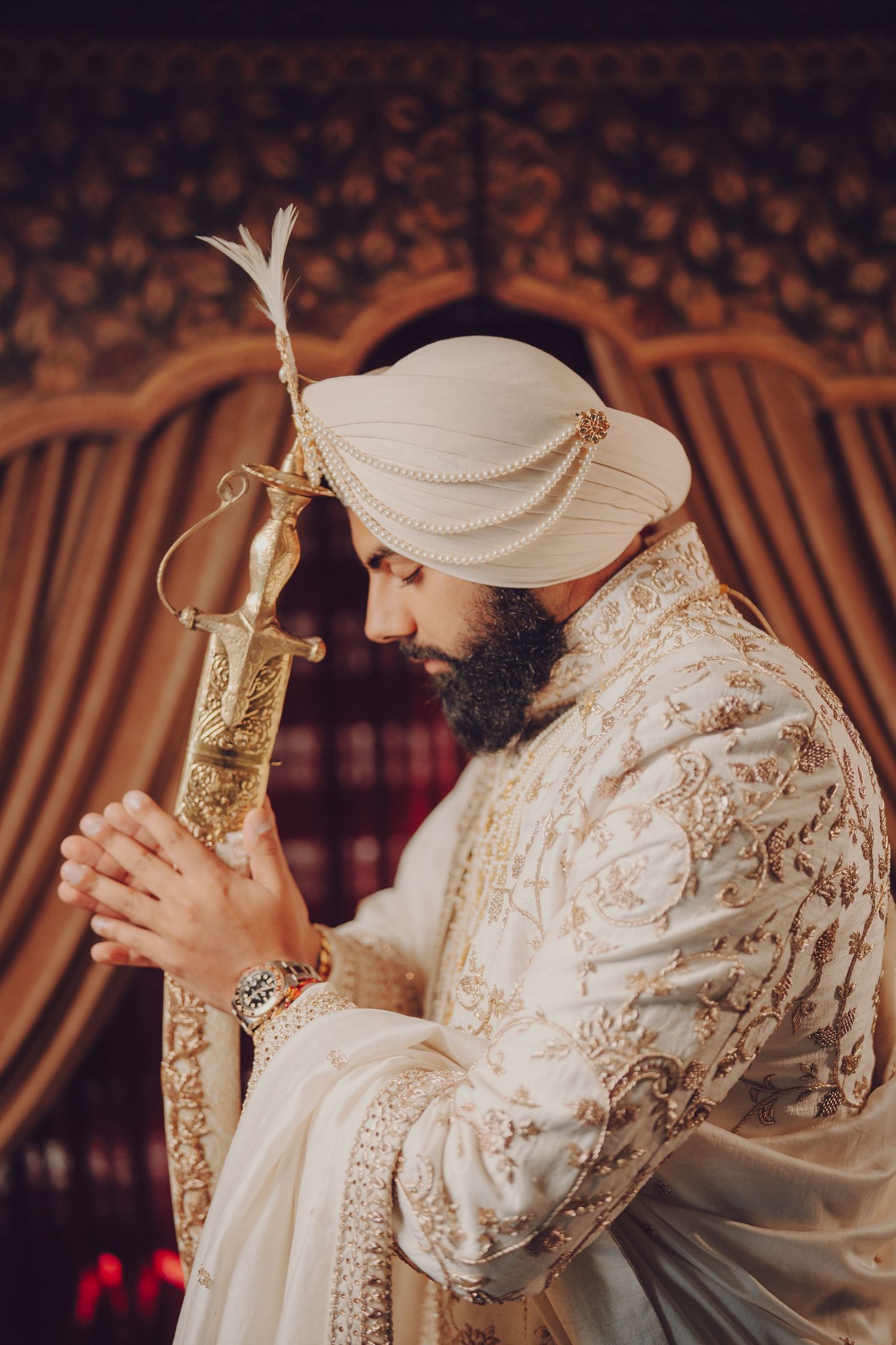 Traditional wedding ceremony detail showing decorative gold bottle against ornate attire.