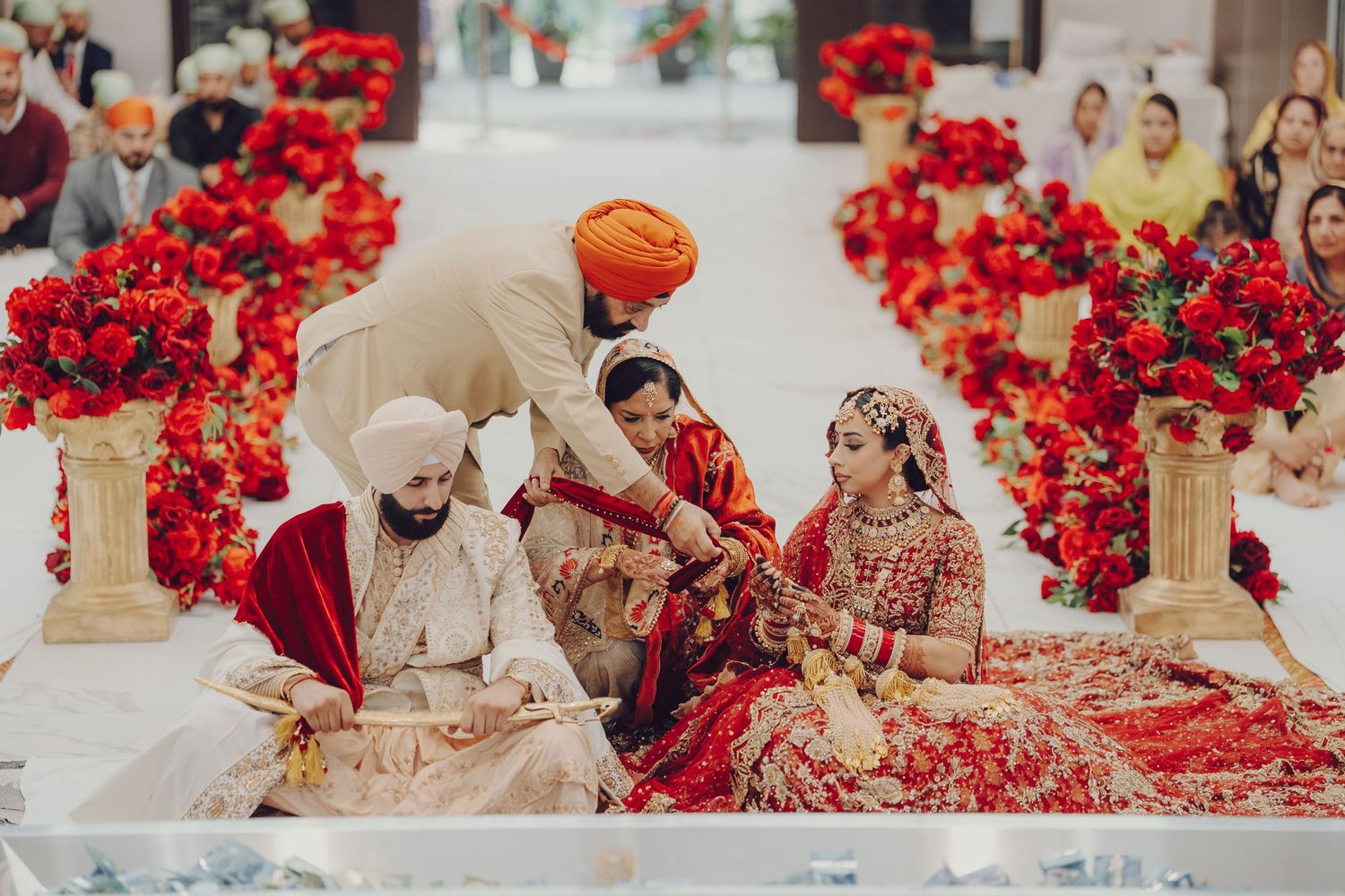 Traditional Sikh wedding ceremony space adorned with bright red floral decorations and elegant attire.