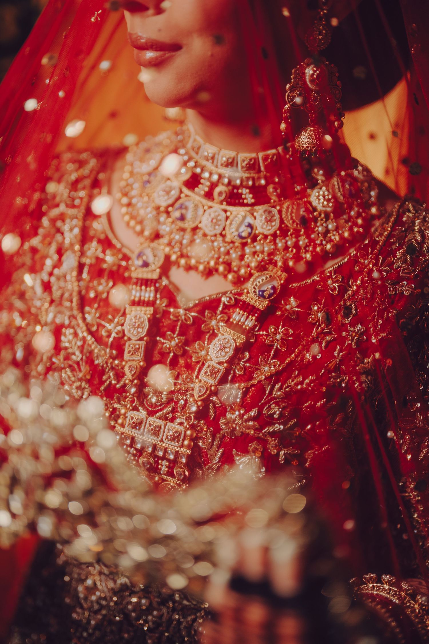 Close-up detail of intricate red and gold Indian bridal jewelry and embroidery.