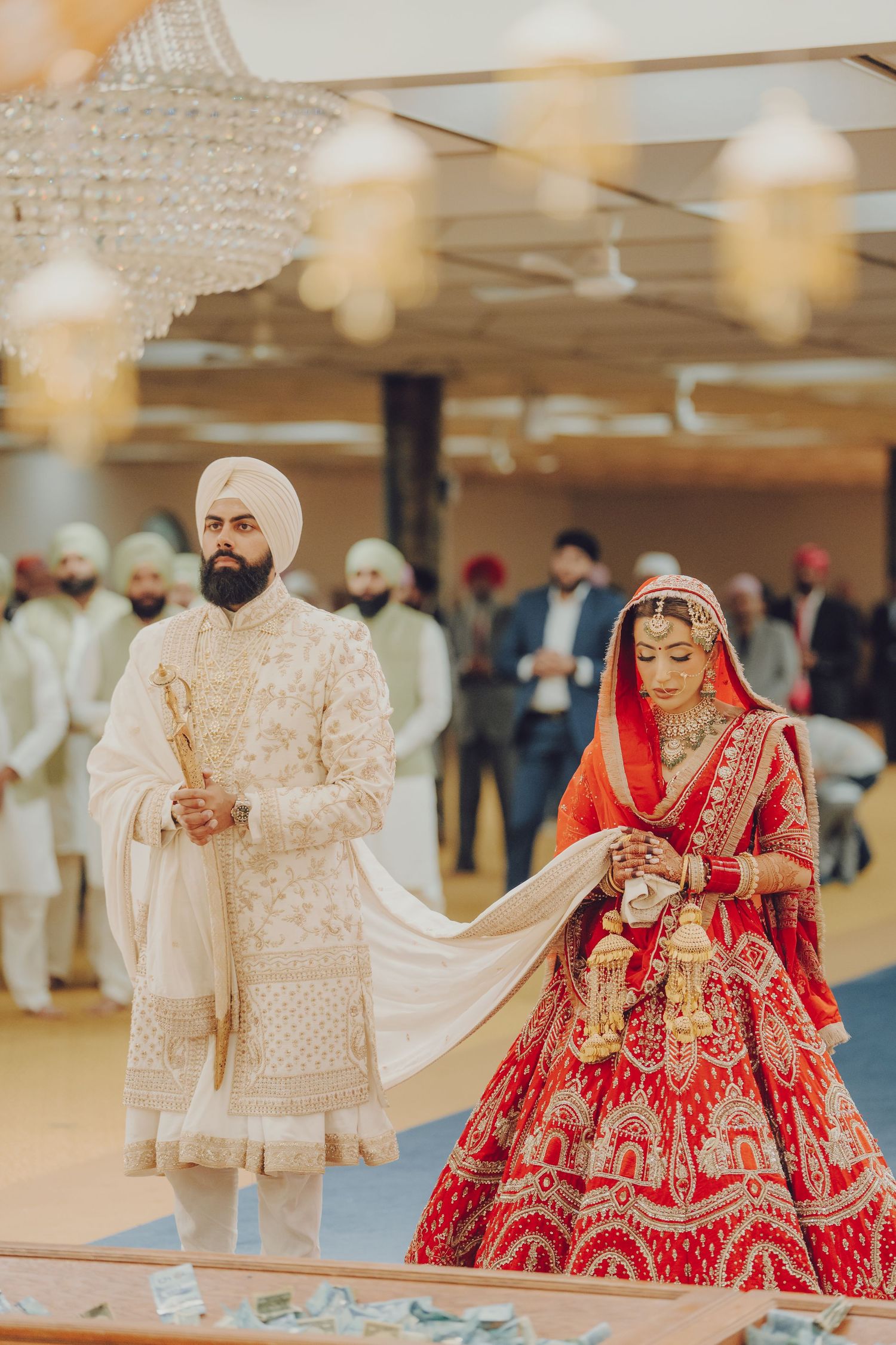 Traditional Indian wedding ceremony with bride in red lehenga and groom in cream sherwani performing rituals.