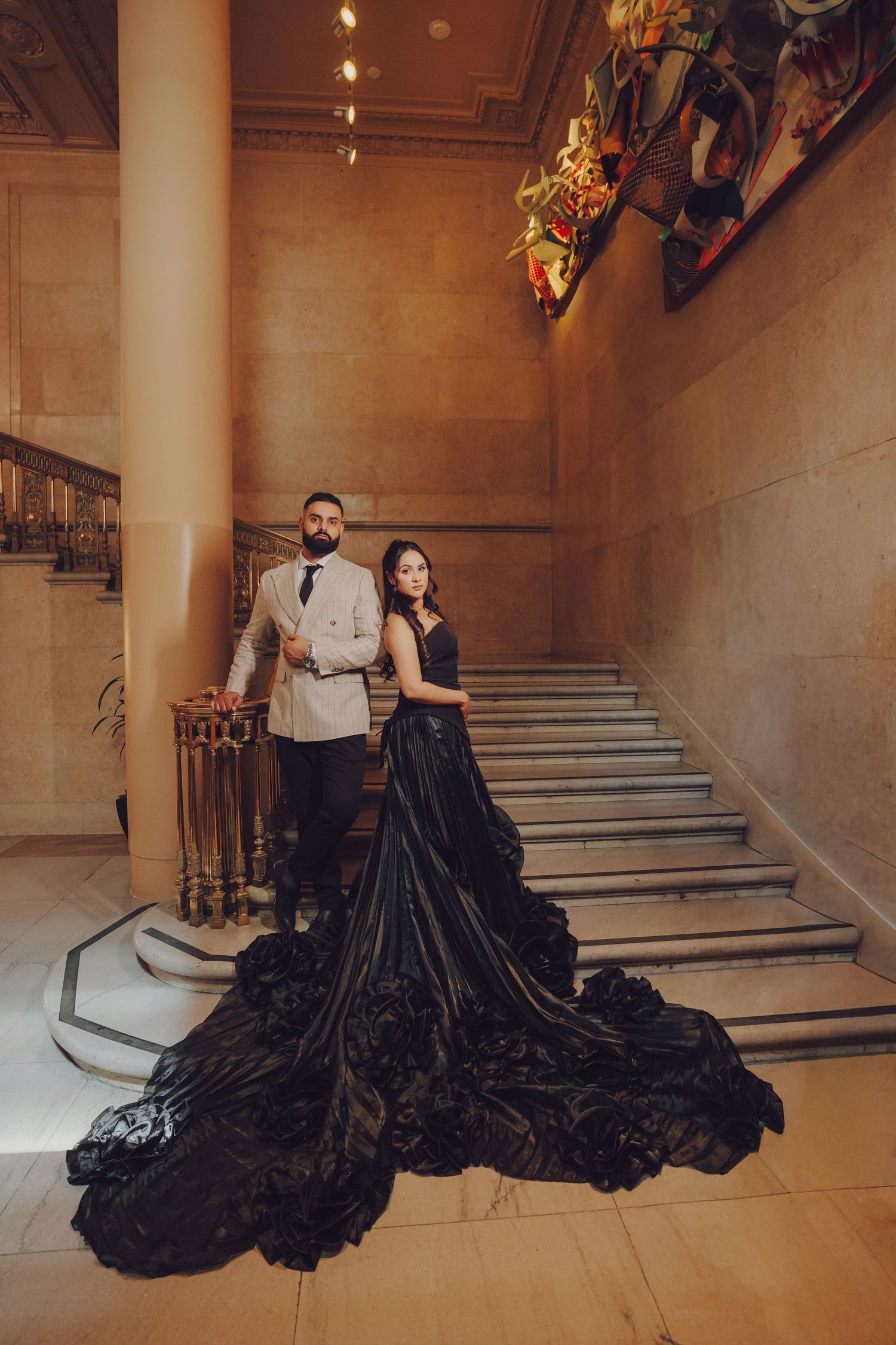 Dramatic black formal gowns sweep across marble floors in an elegant indoor photoshoot.